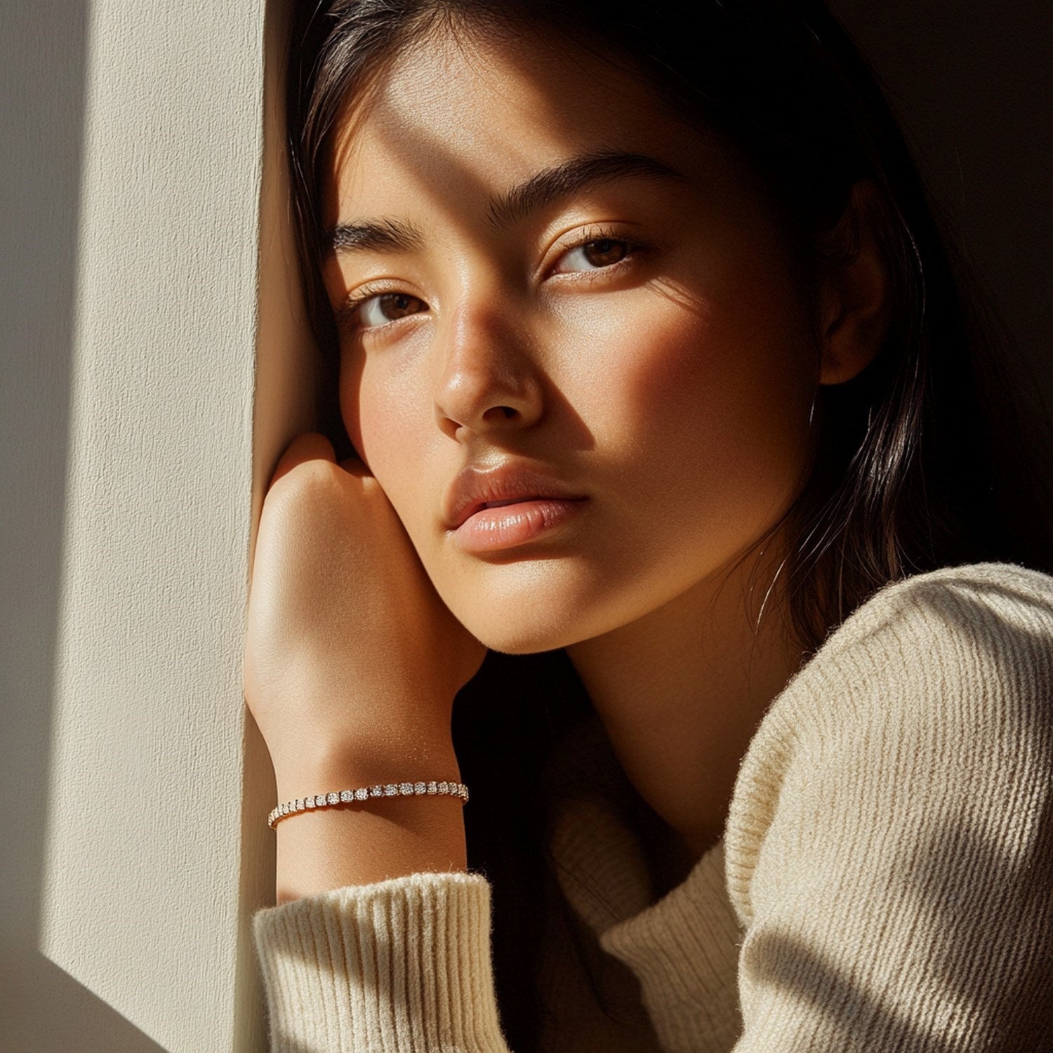 A lab grown round diamond tennis bracelet in 14k yellow gold on a woman's wrist.