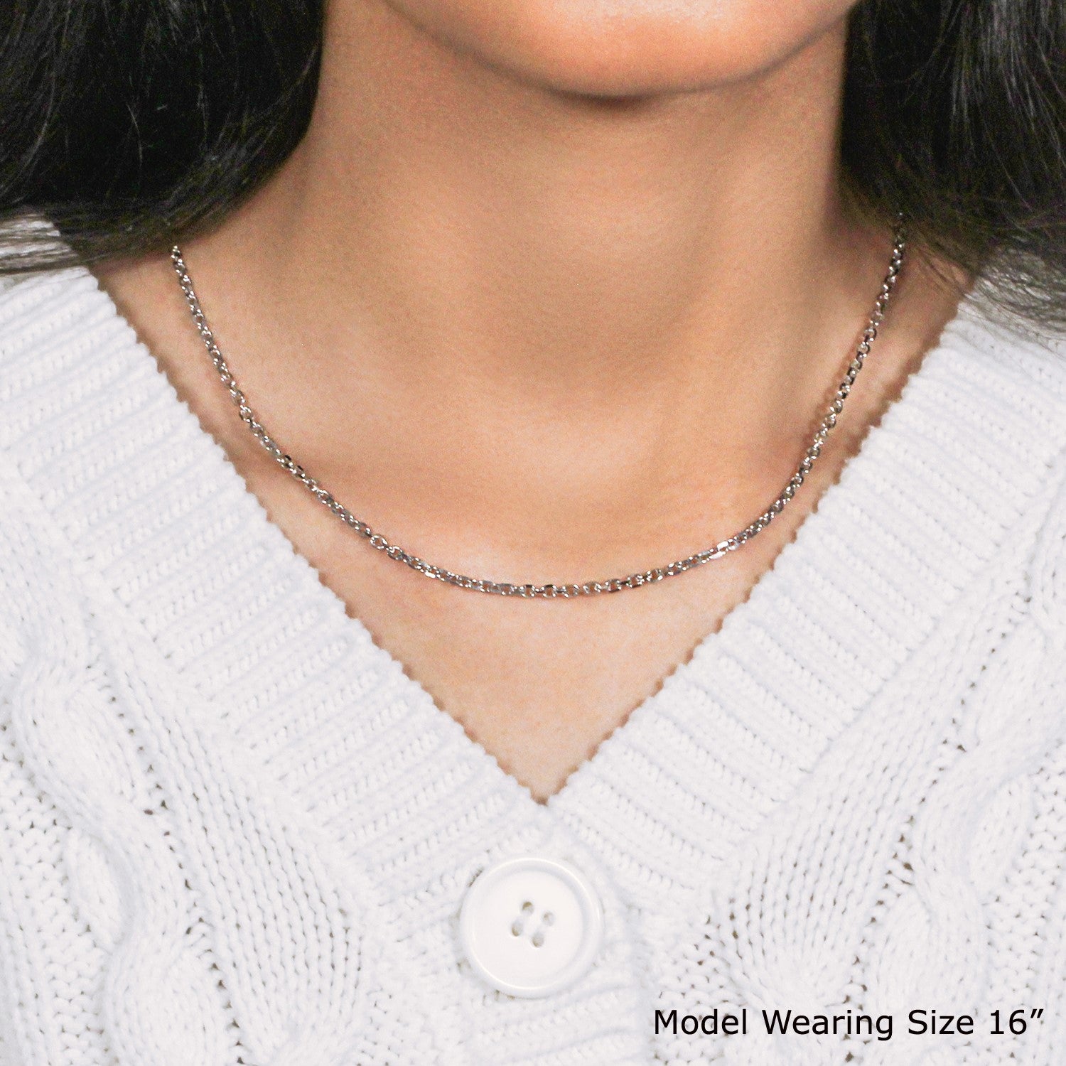 An 18k white gold diamond cut cable link chain is worn around a model's neck.