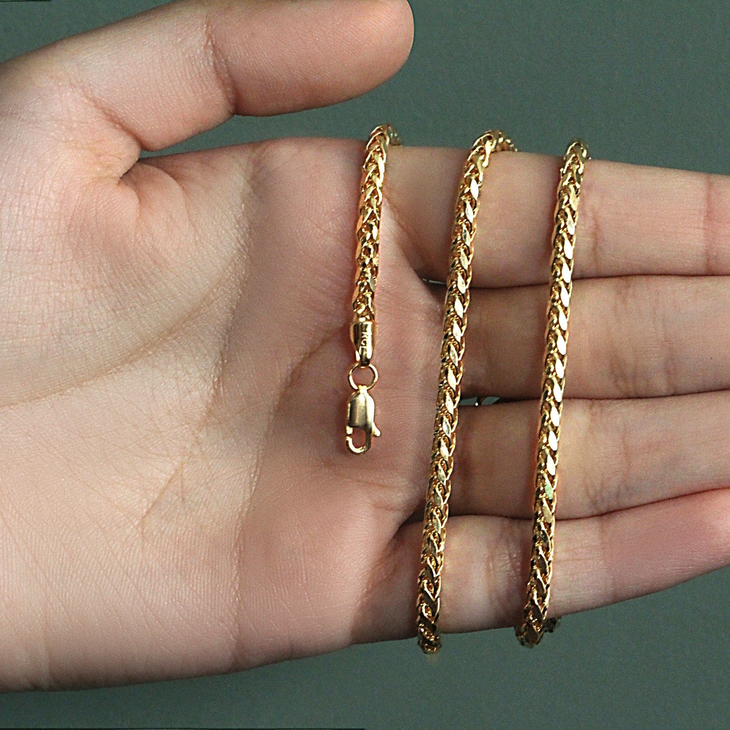 14k yellow gold diamond cut round Franco chain held in an open palm.