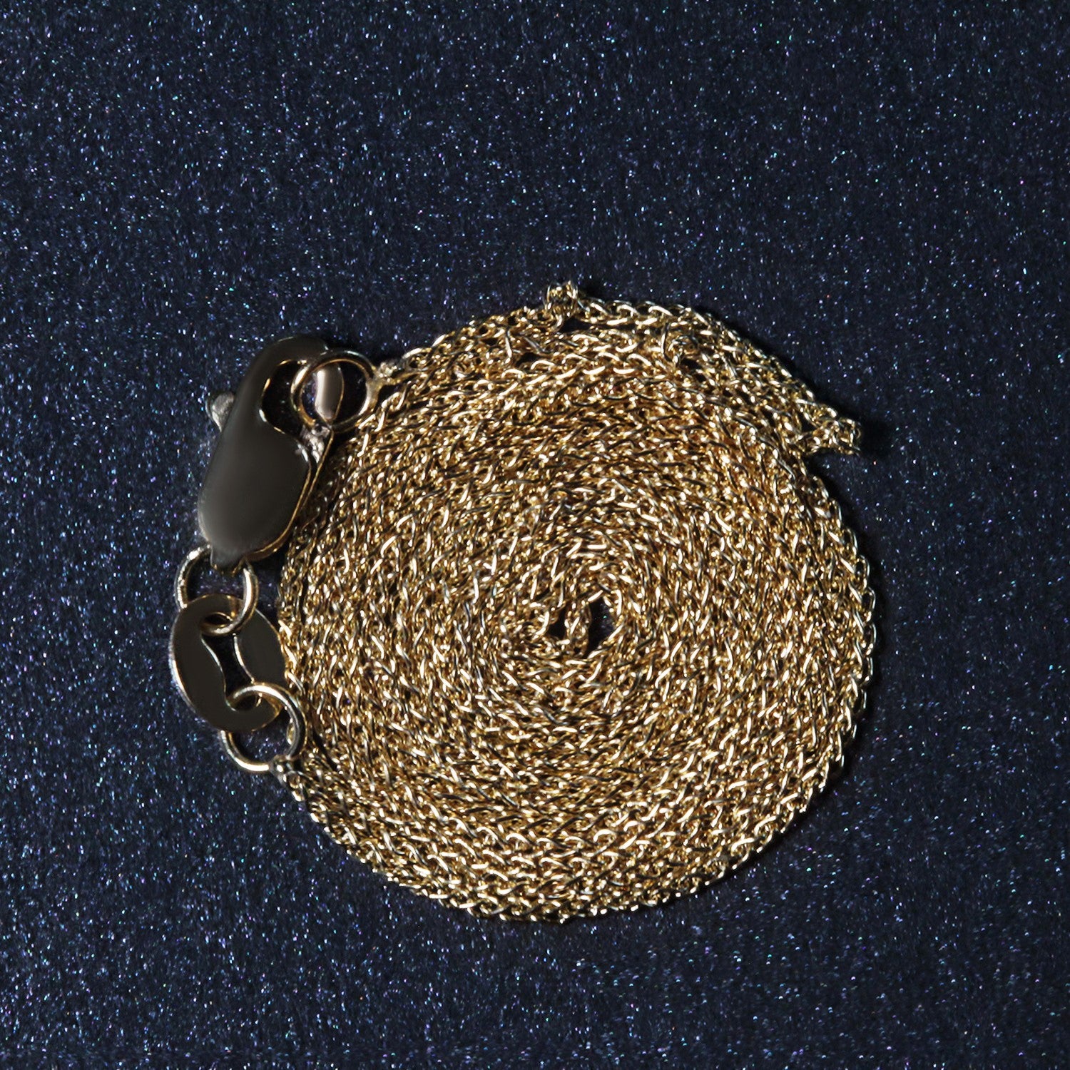 A coiled 14k yellow gold round wheat chain with a lobster clasp.