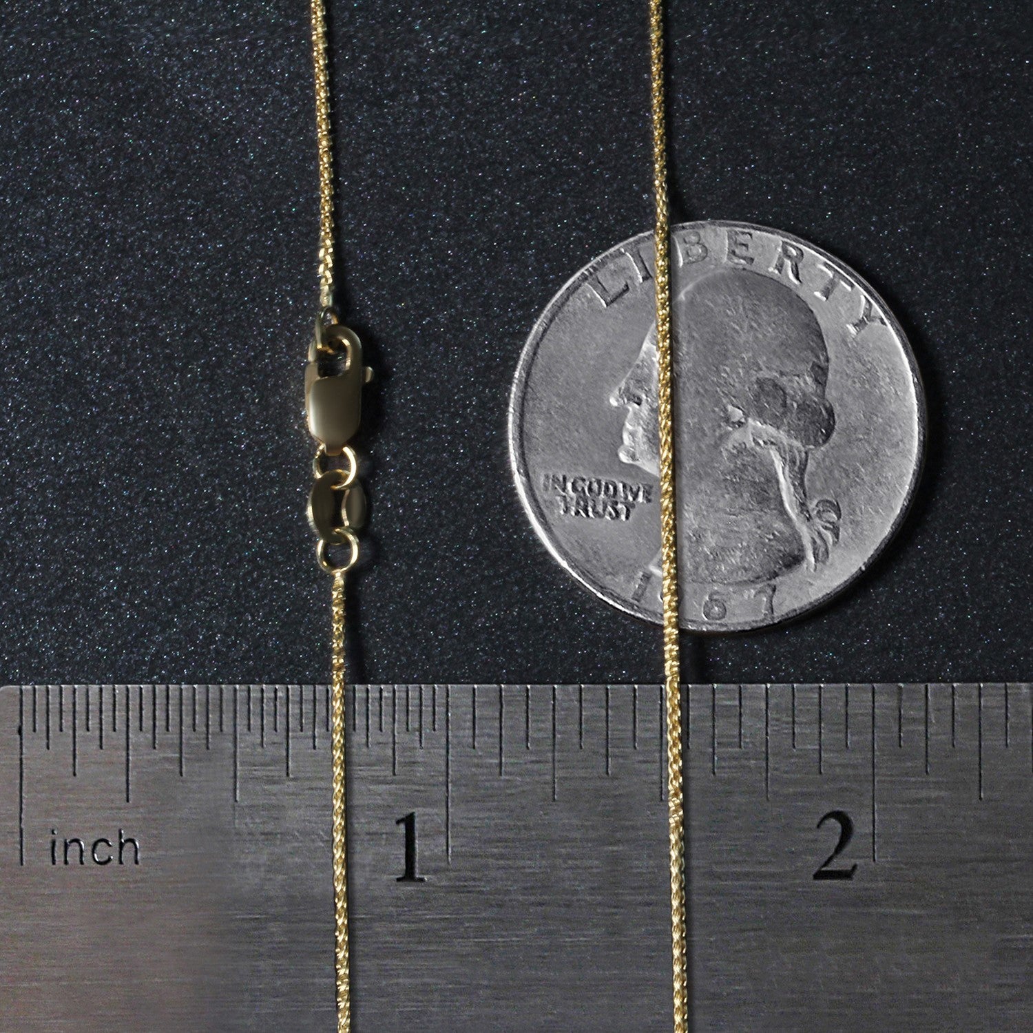 A 14k yellow gold round wheat chain with a lobster clasp, shown next to a ruler and a quarter.