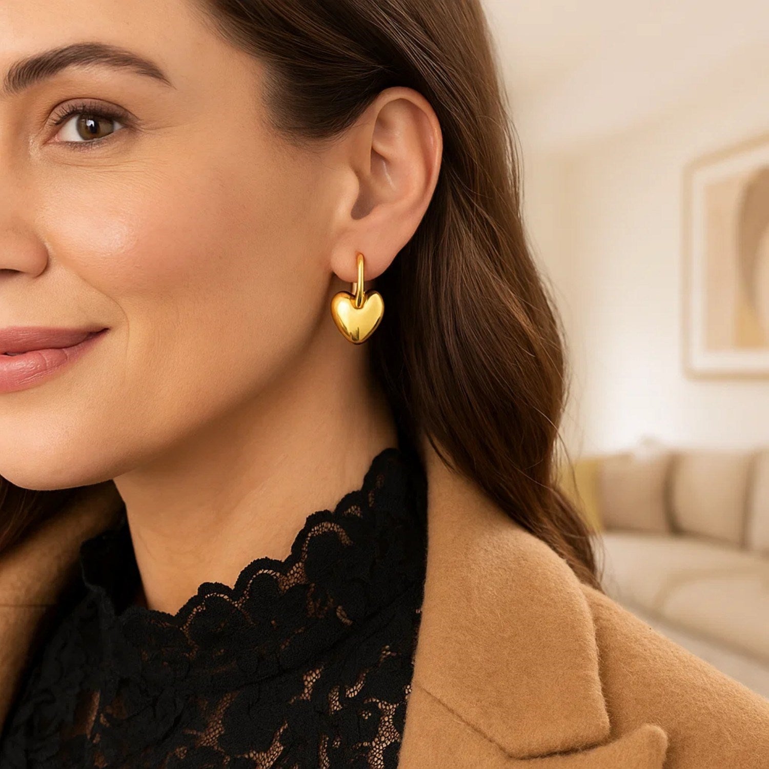 14K yellow gold puffy heart dangle huggie hoop earrings on a woman.