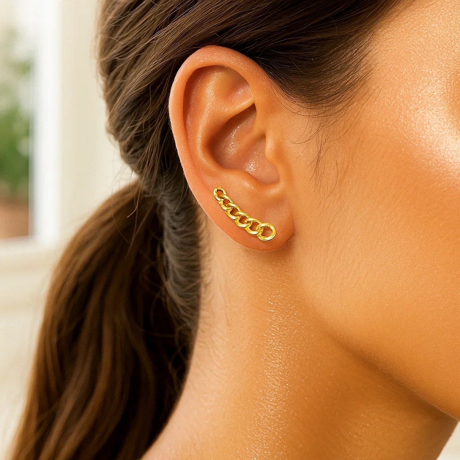 A 14k yellow gold ear climber earring with chain links on a woman's ear.