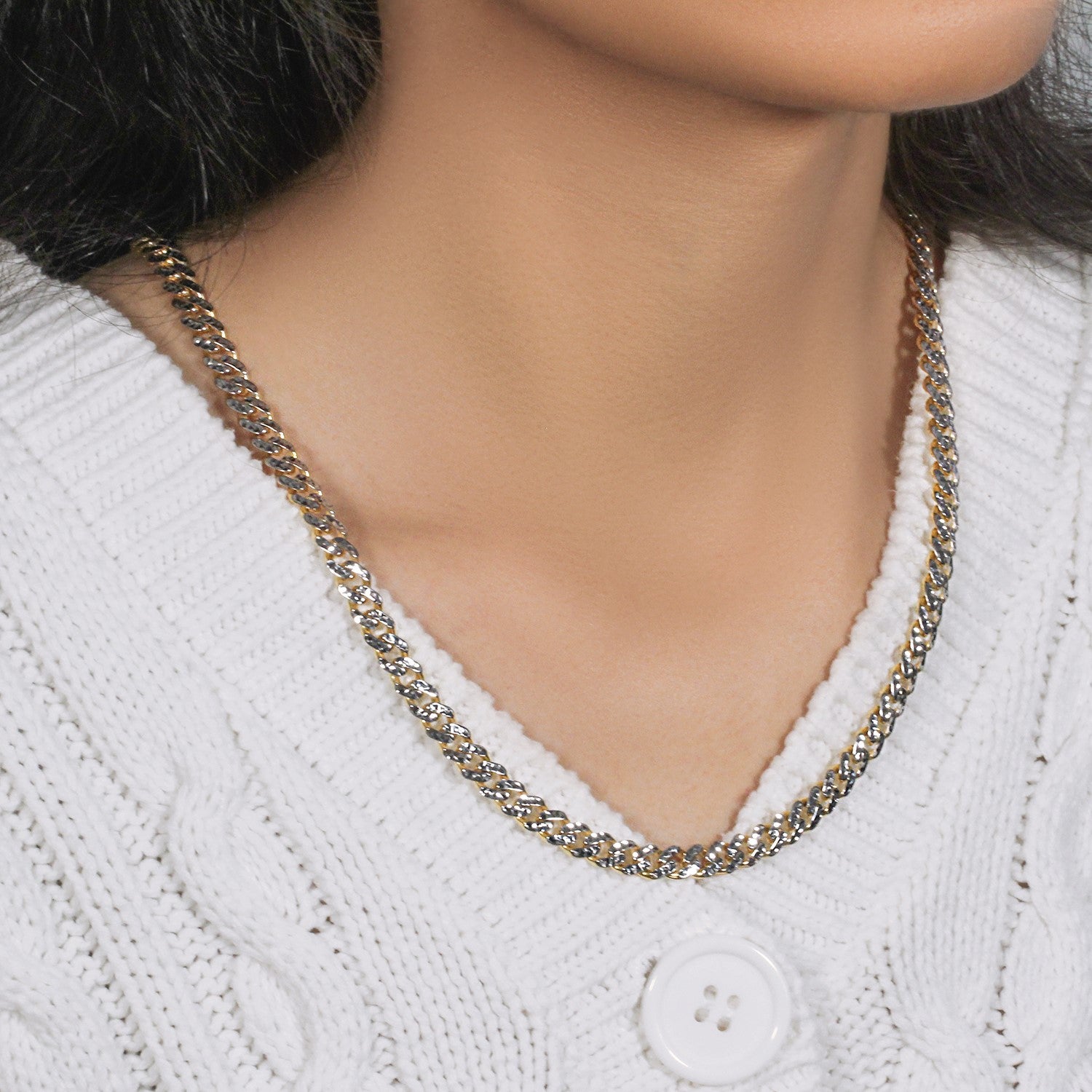 A 14k yellow gold and white pave Miami Cuban chain on a person wearing a white sweater.