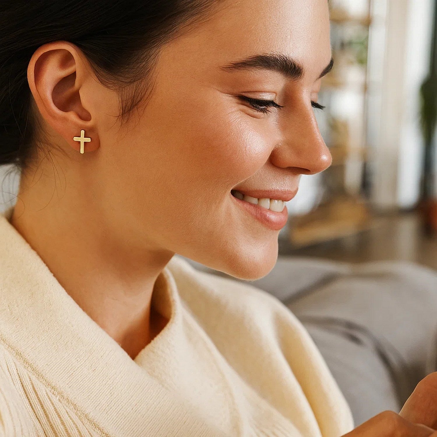 14k yellow gold cross post earrings on a woman's ear.
