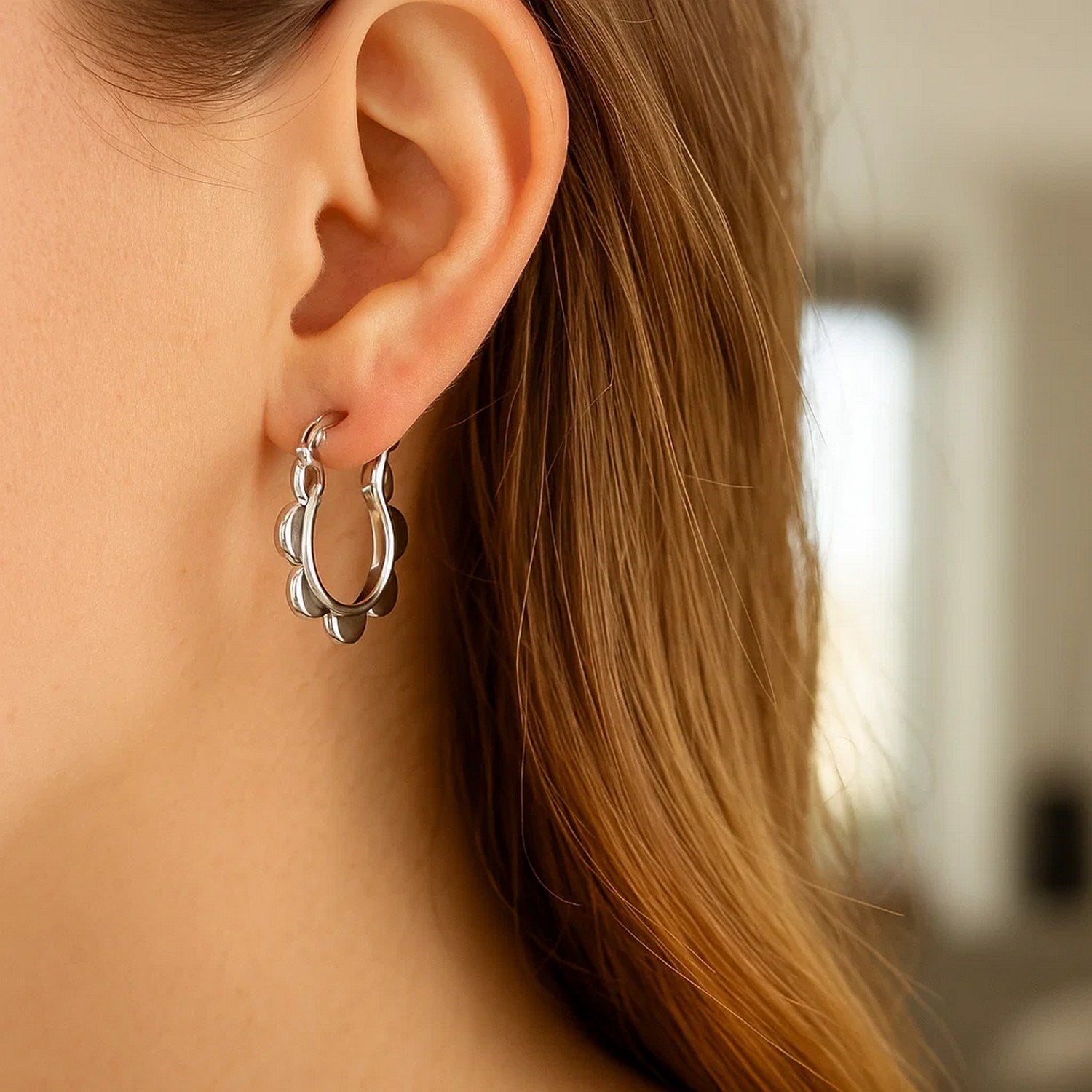 14k white gold scalloped hoop earrings on a model's ear.
