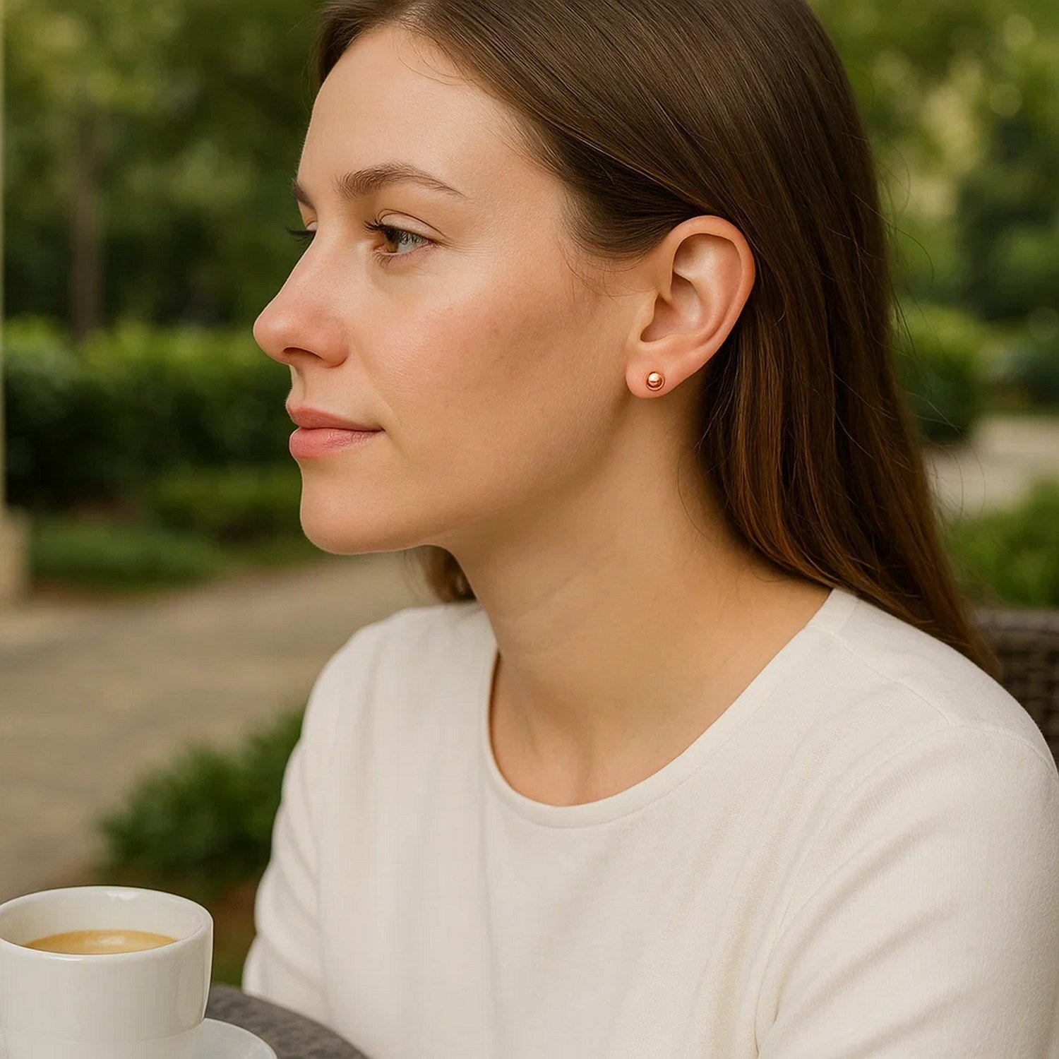 14k rose gold ball style stud earrings on a woman's ear.