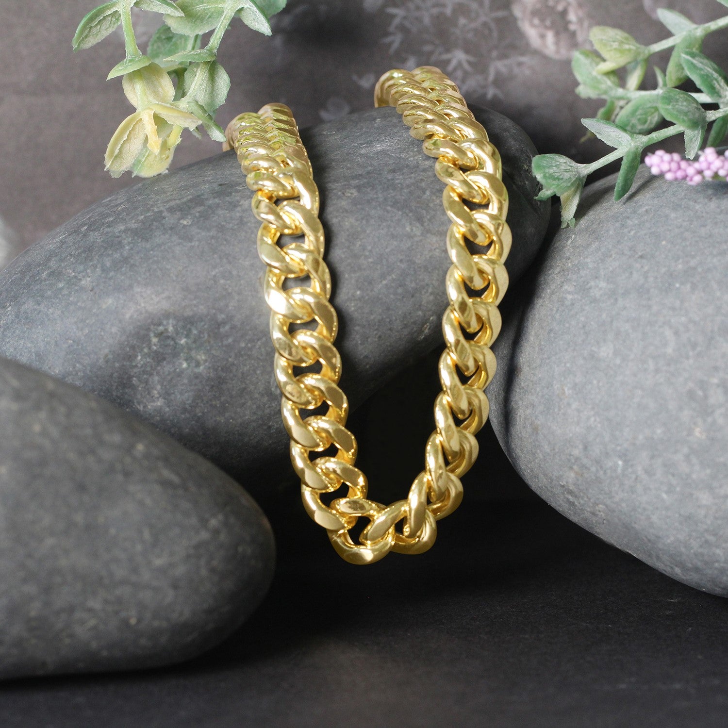 14k yellow gold semi-solid Miami Cuban chain, 9.10 mm wide, displayed on dark rocks.