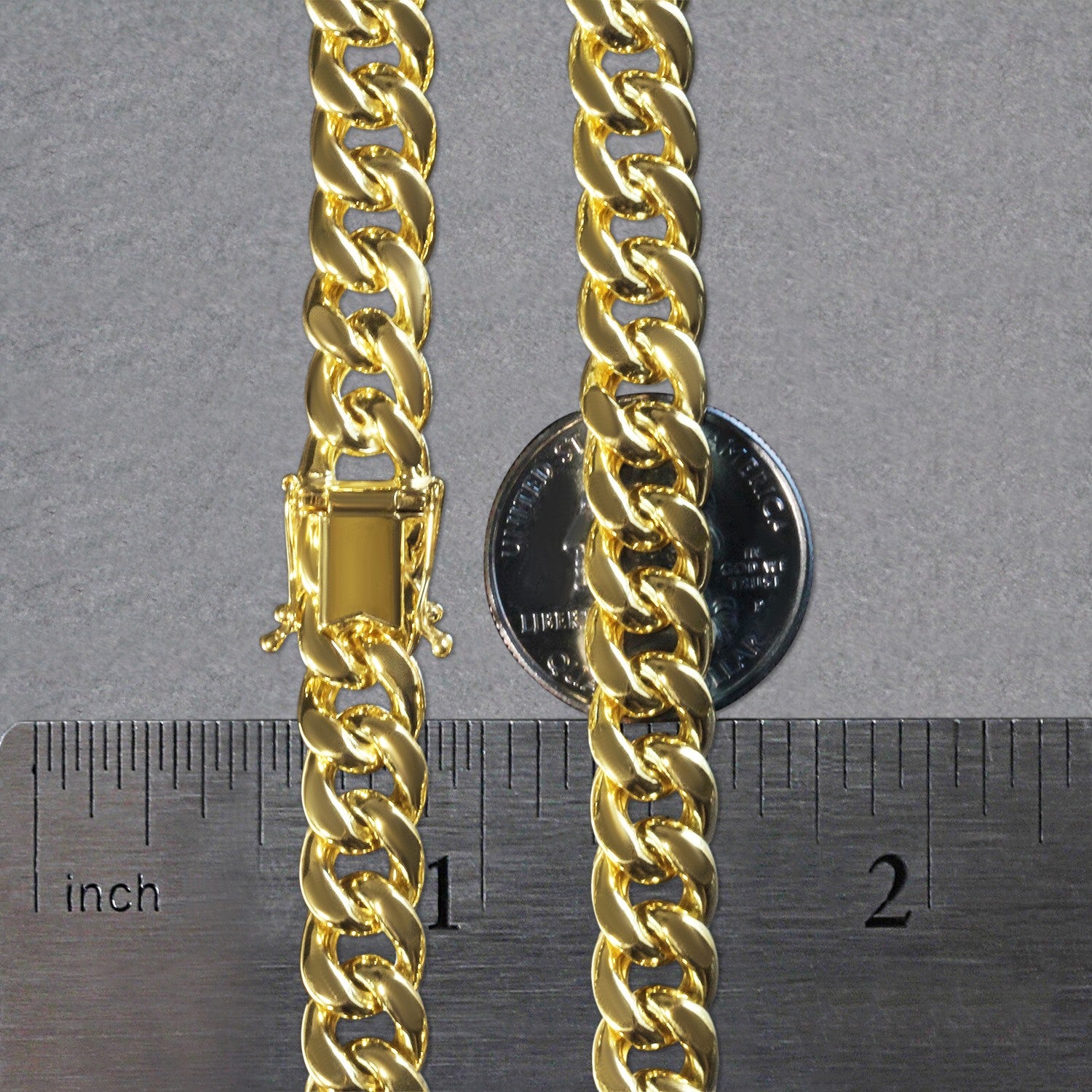 A 14k yellow gold semi-solid Miami Cuban chain with a box clasp, measured against a ruler and coin.