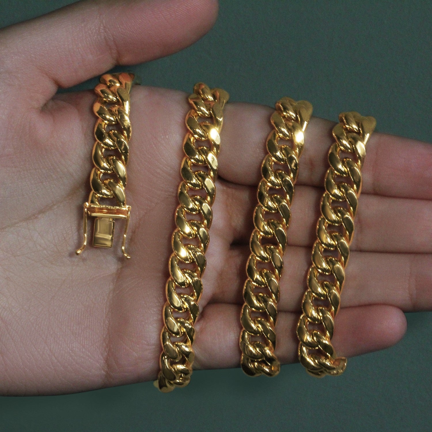 A 14k yellow gold semi-solid Miami Cuban chain with a box clasp, held in a hand.