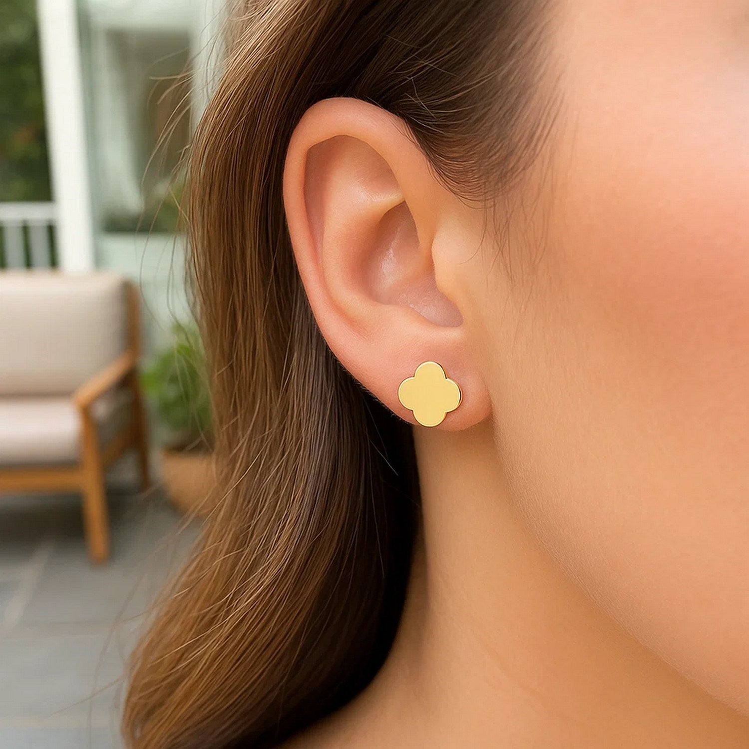 14K yellow gold polished clover stud earrings on a woman's ear.