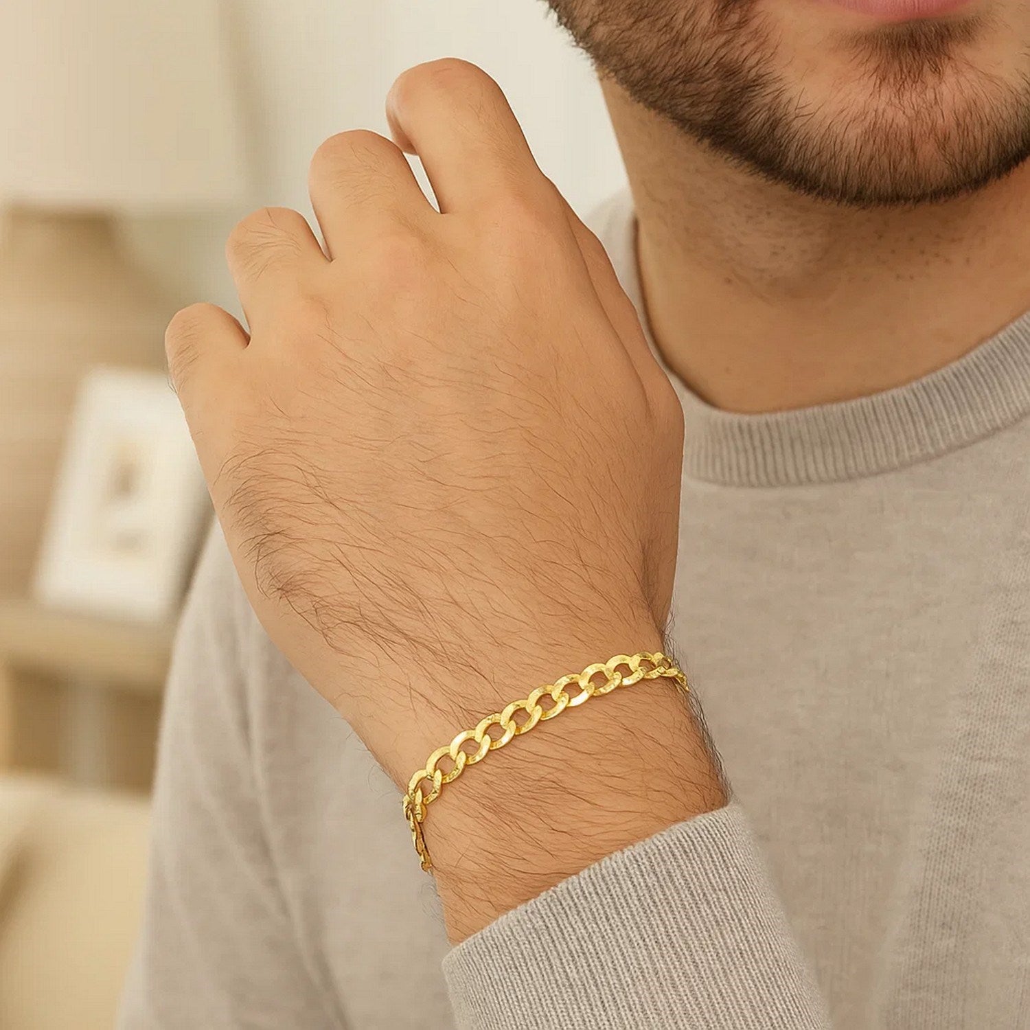 A 10k yellow gold curb bracelet is worn on a man's wrist.