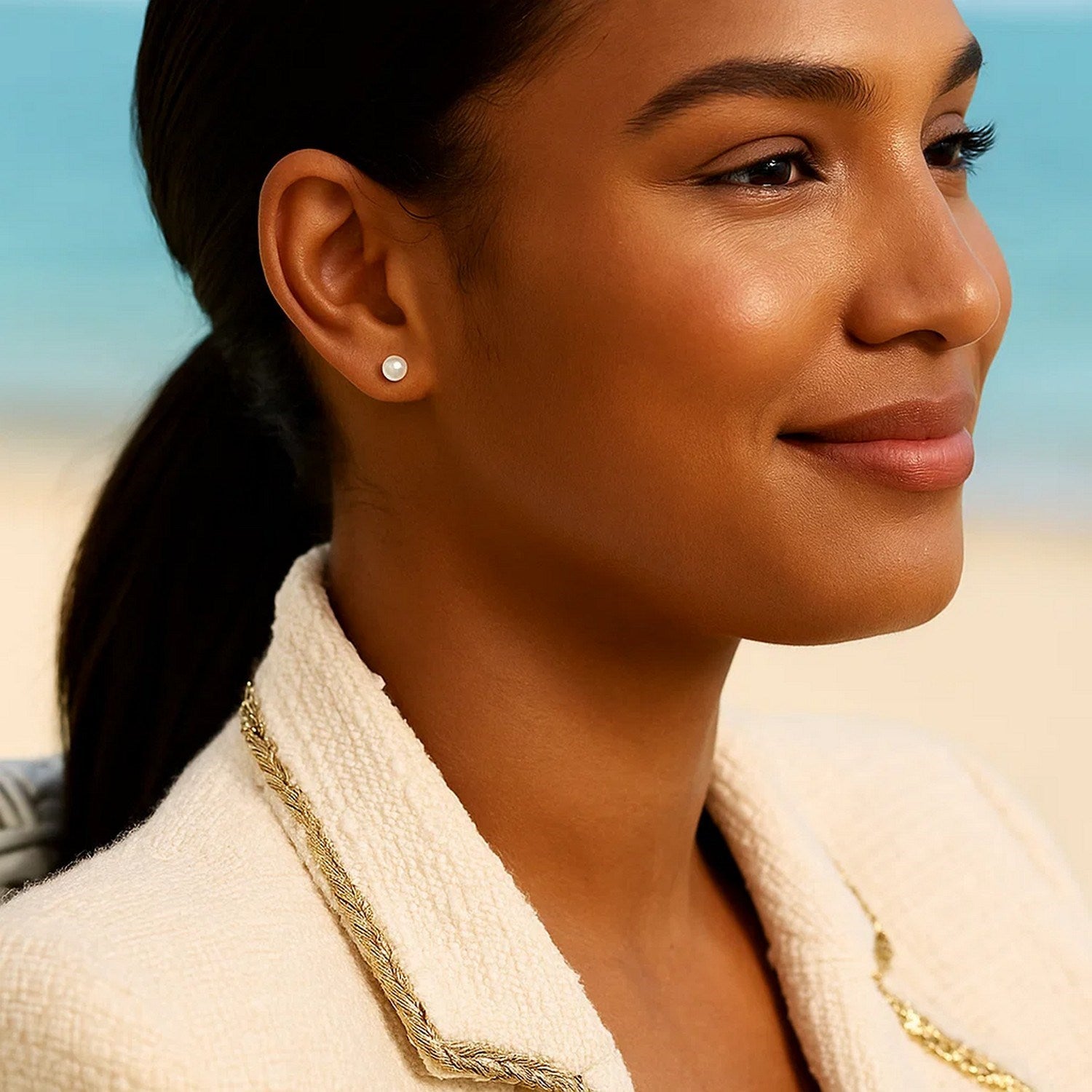 14k yellow gold freshwater cultured white pearl stud earrings on a woman's ear.