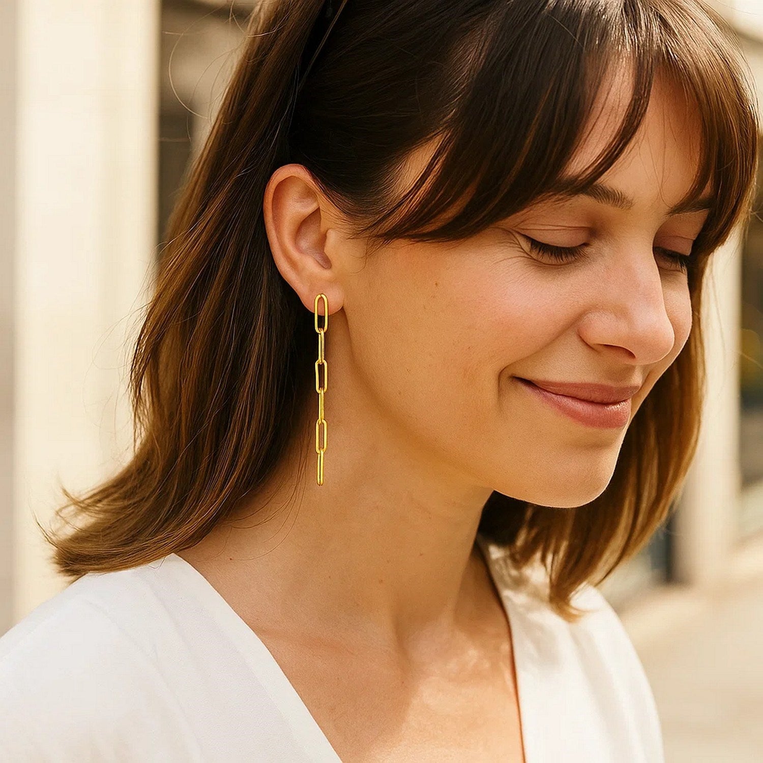 14K yellow gold five-link paperclip chain earrings dangle from a woman's ear.