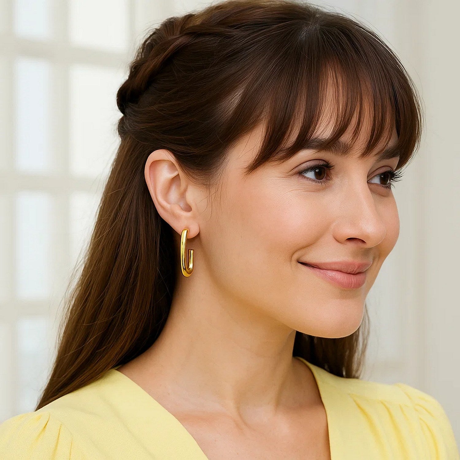 14K yellow gold paperclip hoop earrings on a woman.
