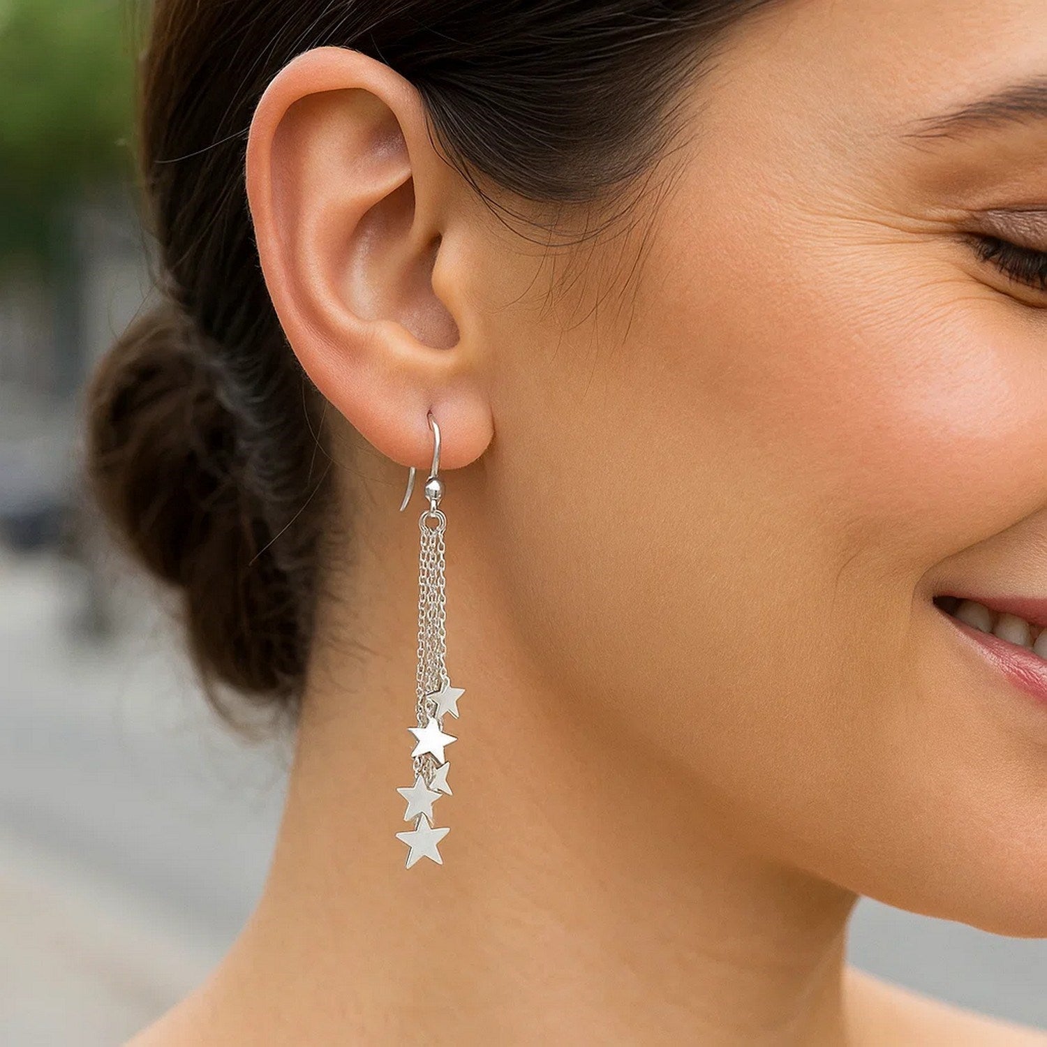 Sterling silver tassel earrings with polished stars dangle from a woman's ear.