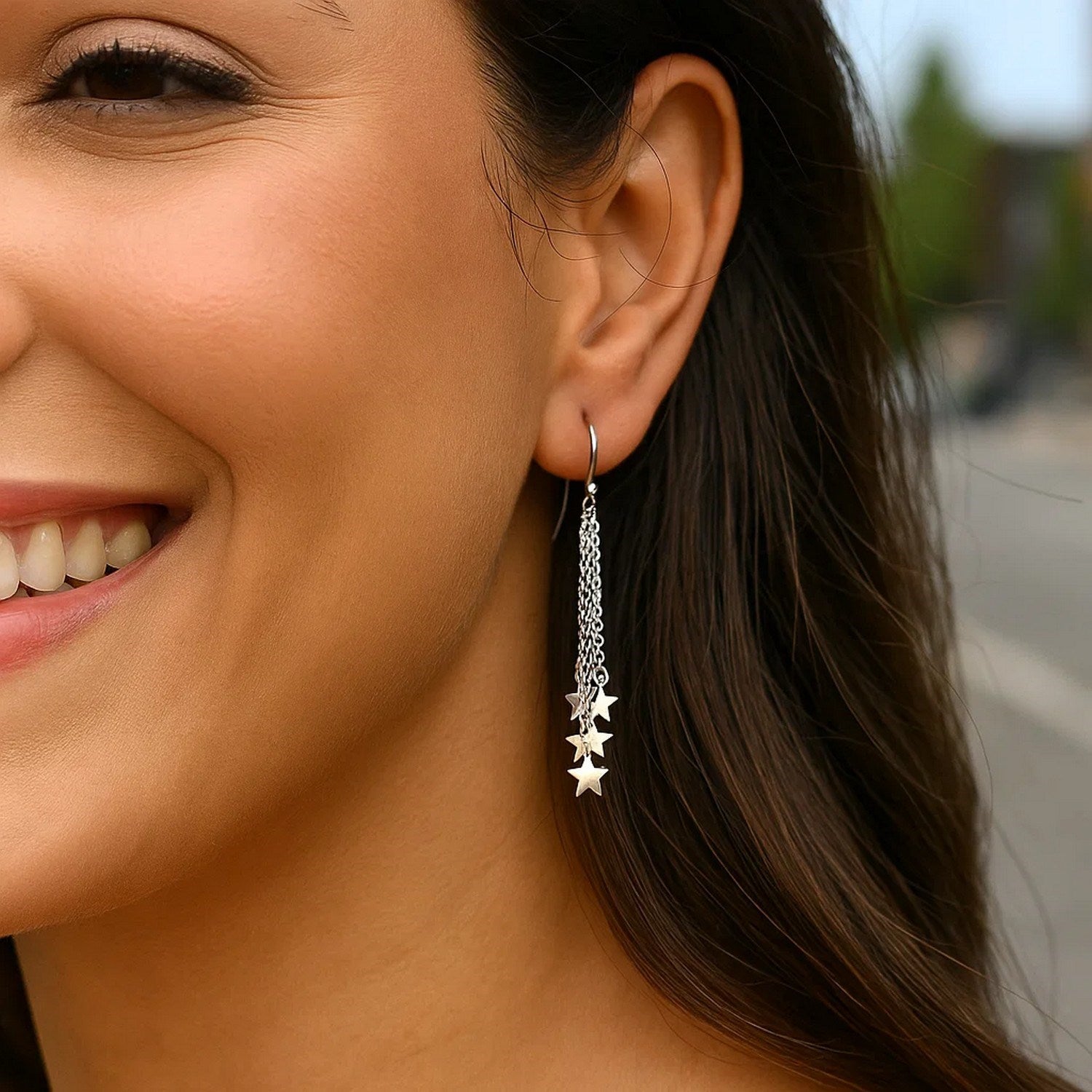 Sterling silver tassel earrings with polished stars on a woman's ear.