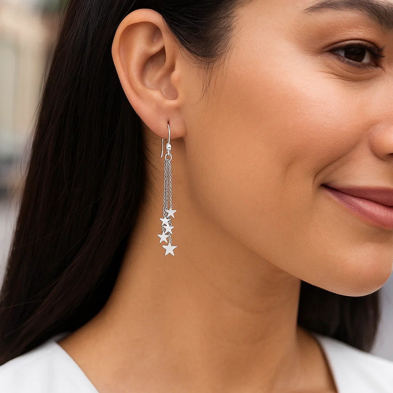 Sterling silver tassel earrings with polished stars dangle from a woman's ear.