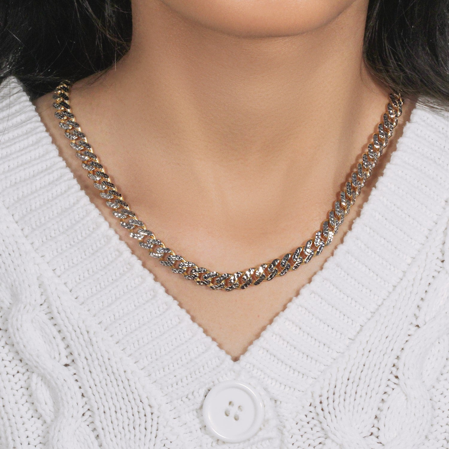 A two-tone 14k gold Miami Cuban chain with white pave links on a person's neck.