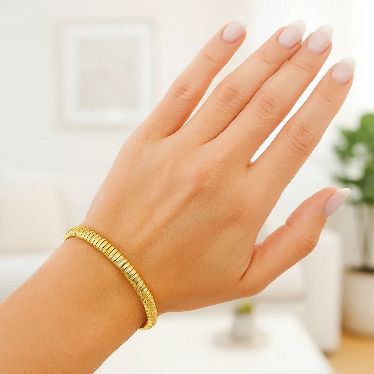 A 14K yellow gold Tubogas bracelet with a 5.00 mm width on a woman's wrist.