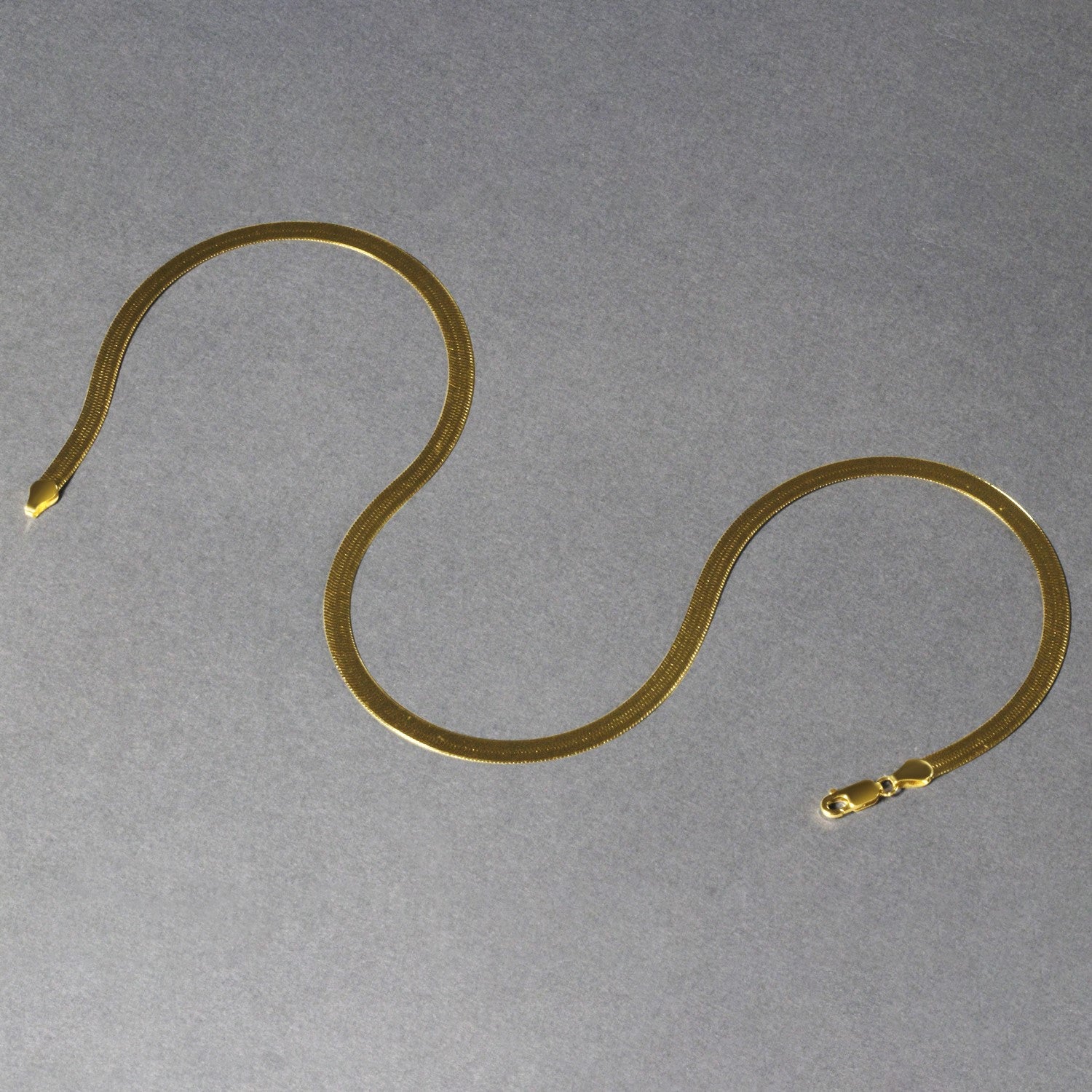 A 14k yellow gold super flex herringbone chain with a lobster clasp.