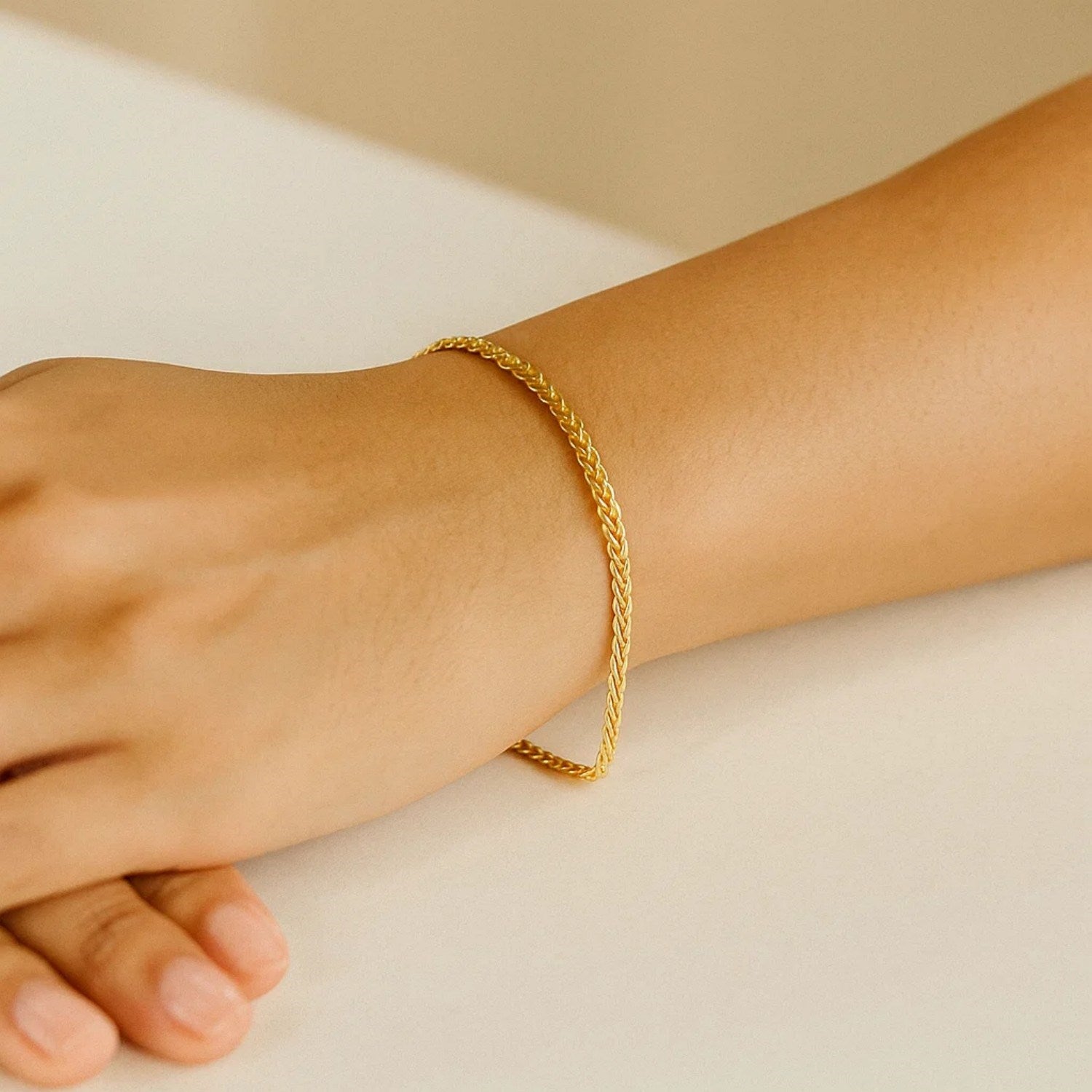 A 10k yellow gold wheat chain bracelet on a person's wrist.