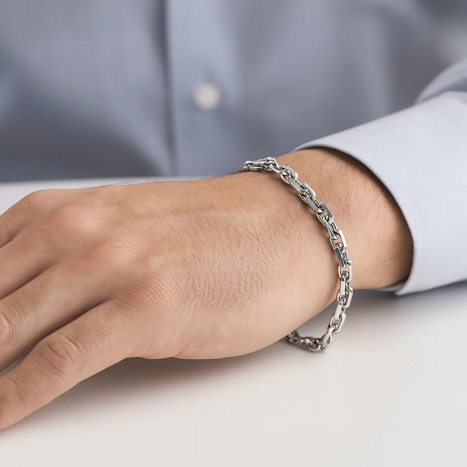 A 14k white gold French cable chain bracelet on a man's wrist.