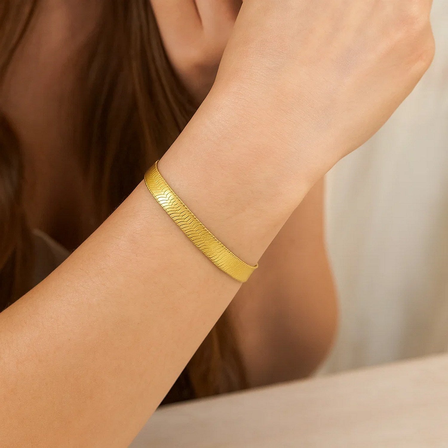 14k yellow gold super flex herringbone bracelet on a person's wrist.