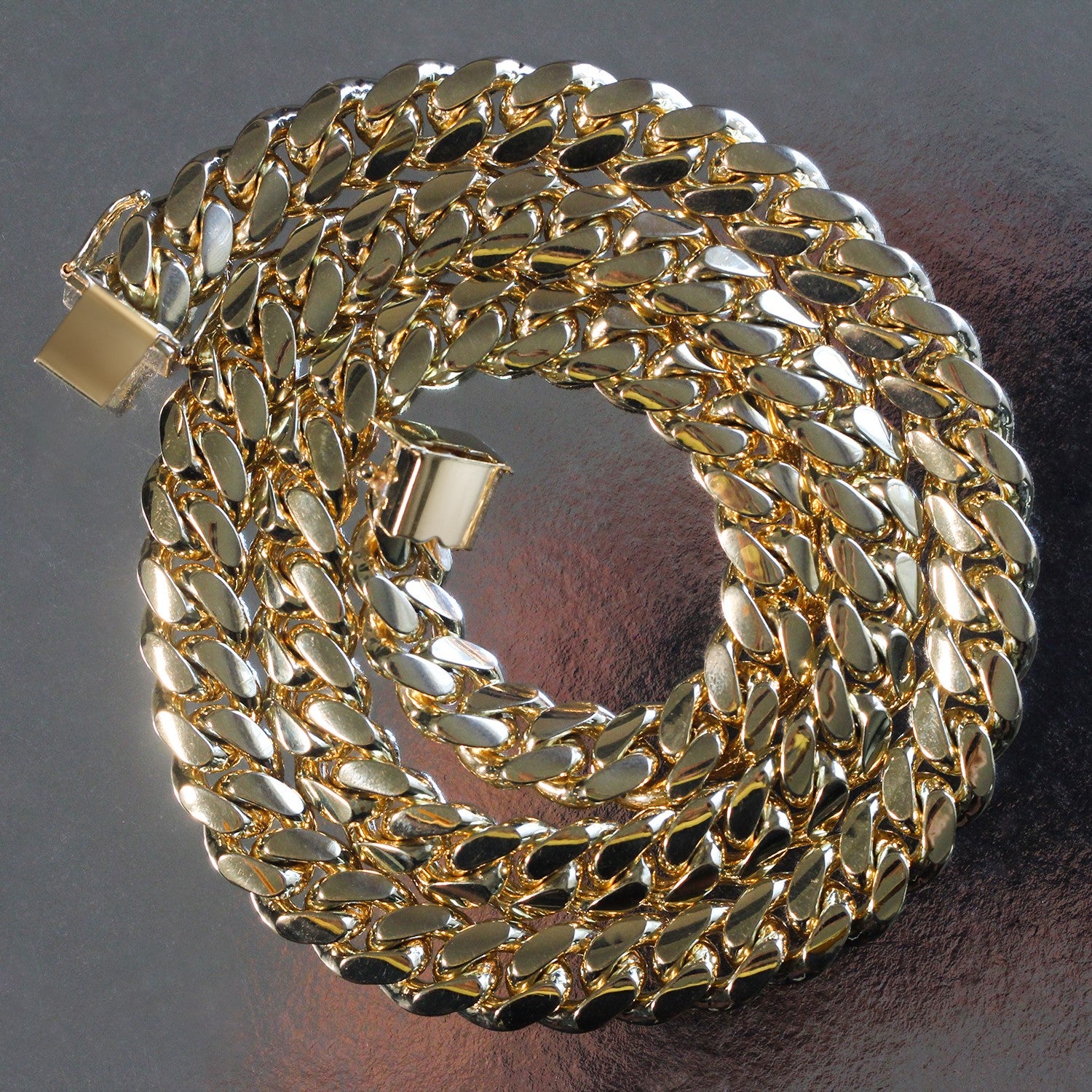 A 14k yellow gold classic Miami Cuban solid chain, 10.10 mm wide, coiled on a dark surface.