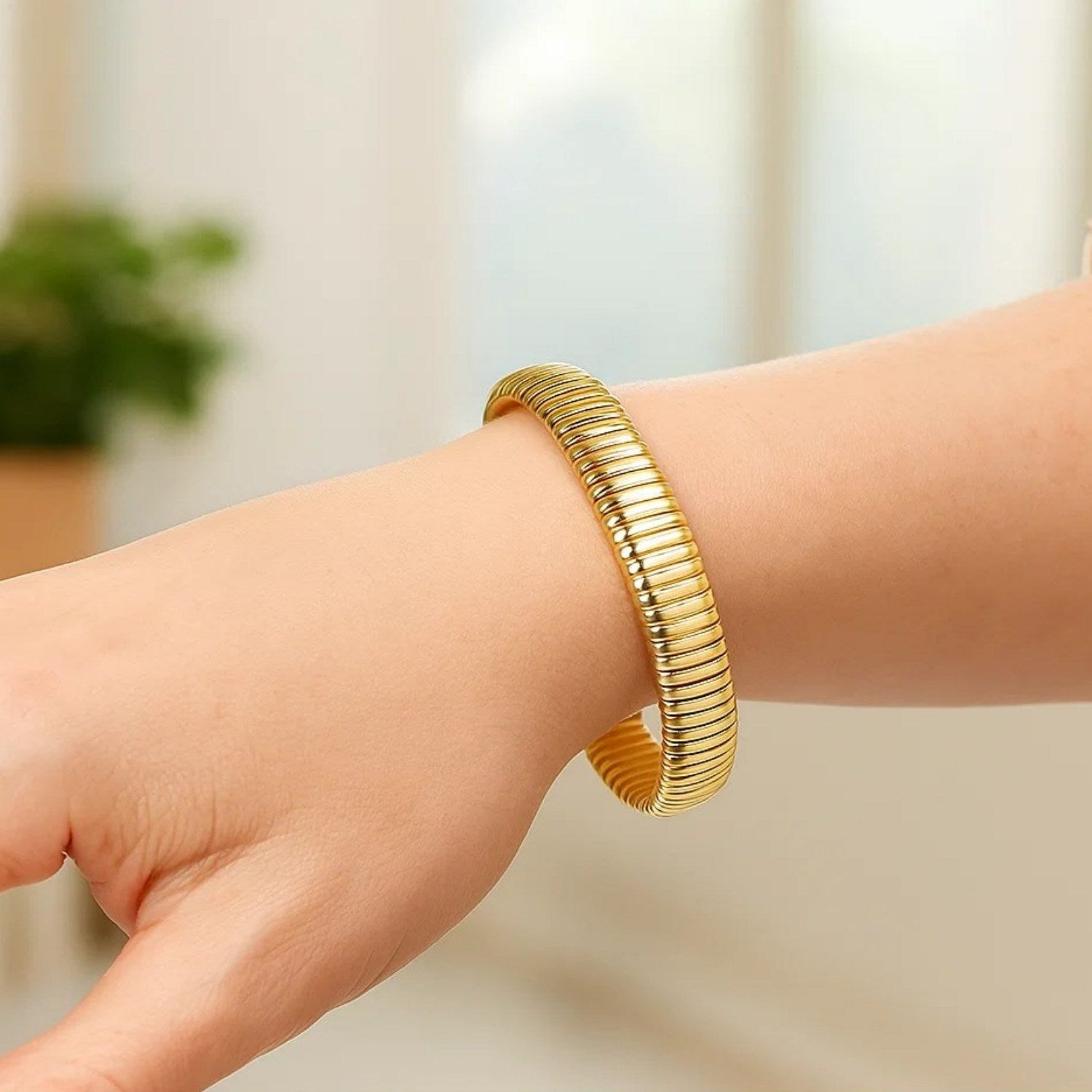 A 14K yellow gold tubogas bracelet with smooth, tubular links on a wrist.