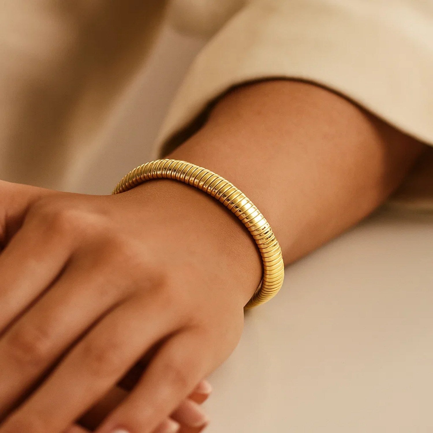 A 14K yellow gold tubogas bracelet is worn on a person's wrist.