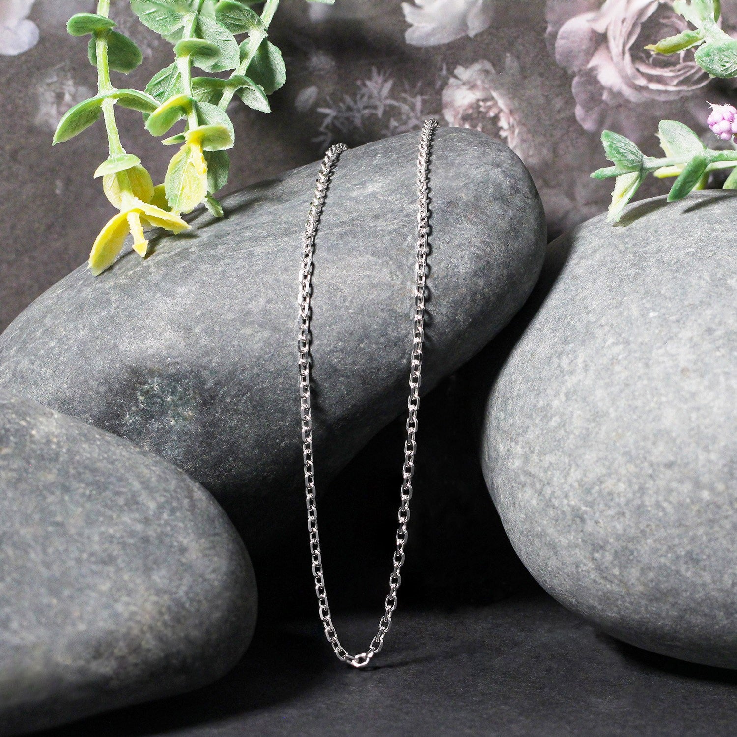 18k white gold diamond cut cable link chain displayed on dark grey stones.
