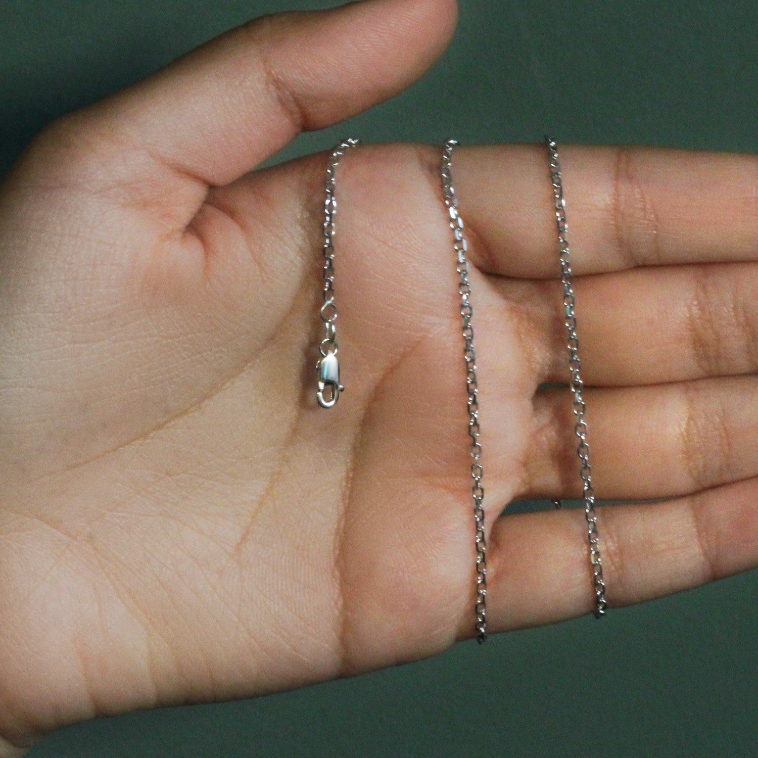 18k white gold diamond cut cable link chain with a lobster clasp on a hand.