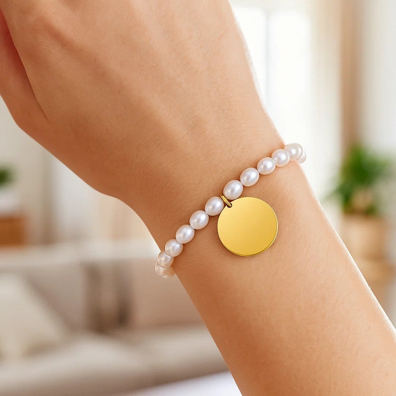A woman's arm wears a 14k yellow gold pearl tag charm bracelet.