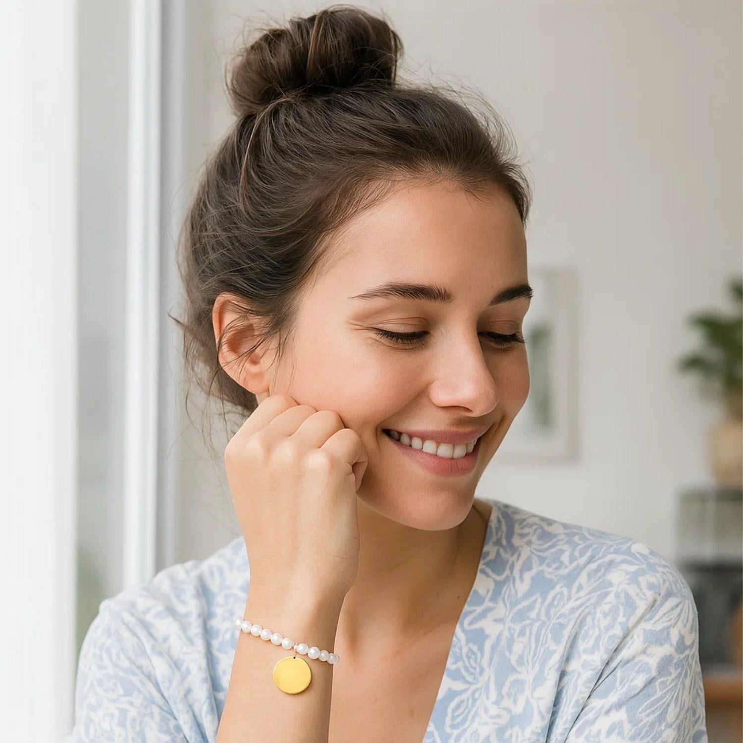14k yellow gold pearl tag charm bracelet on a woman's wrist.