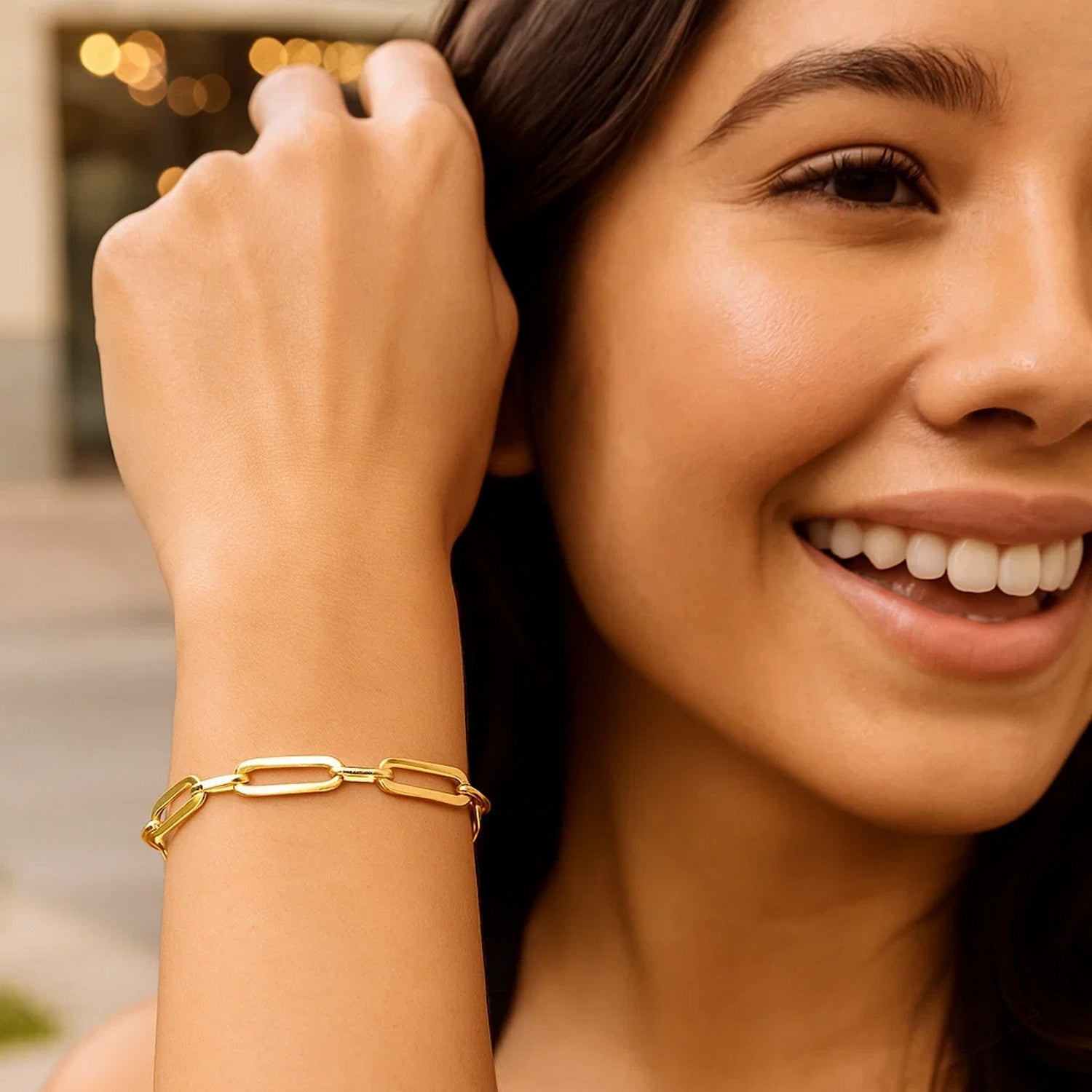 A woman wears a 14k yellow gold Bombay paperclip chain bracelet.