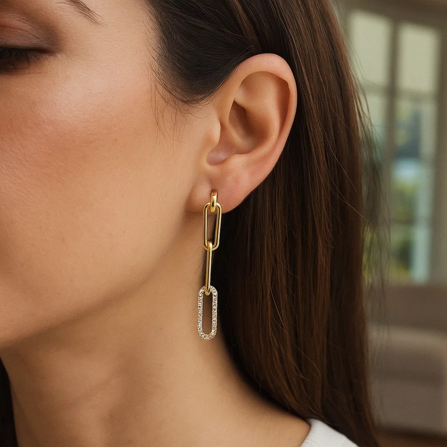 14k yellow gold paperclip chain dangle earrings with diamonds on a woman's ear.