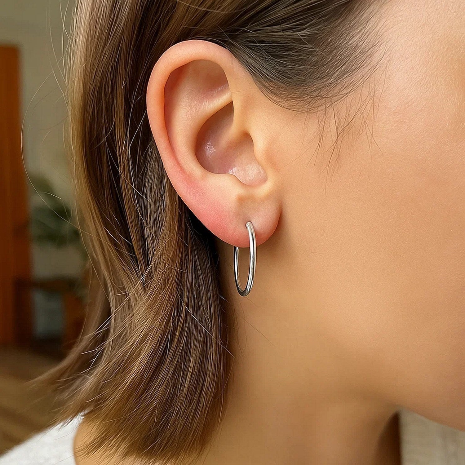 10k white gold polished hoop earrings on a person's ear.