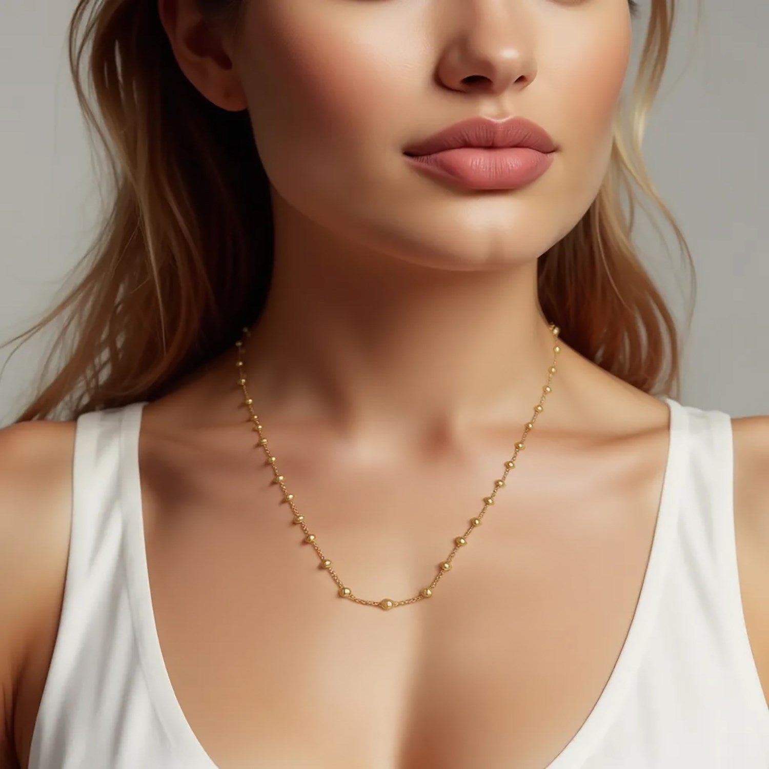 A woman wears a 14K yellow gold layering Saturn bead necklace.