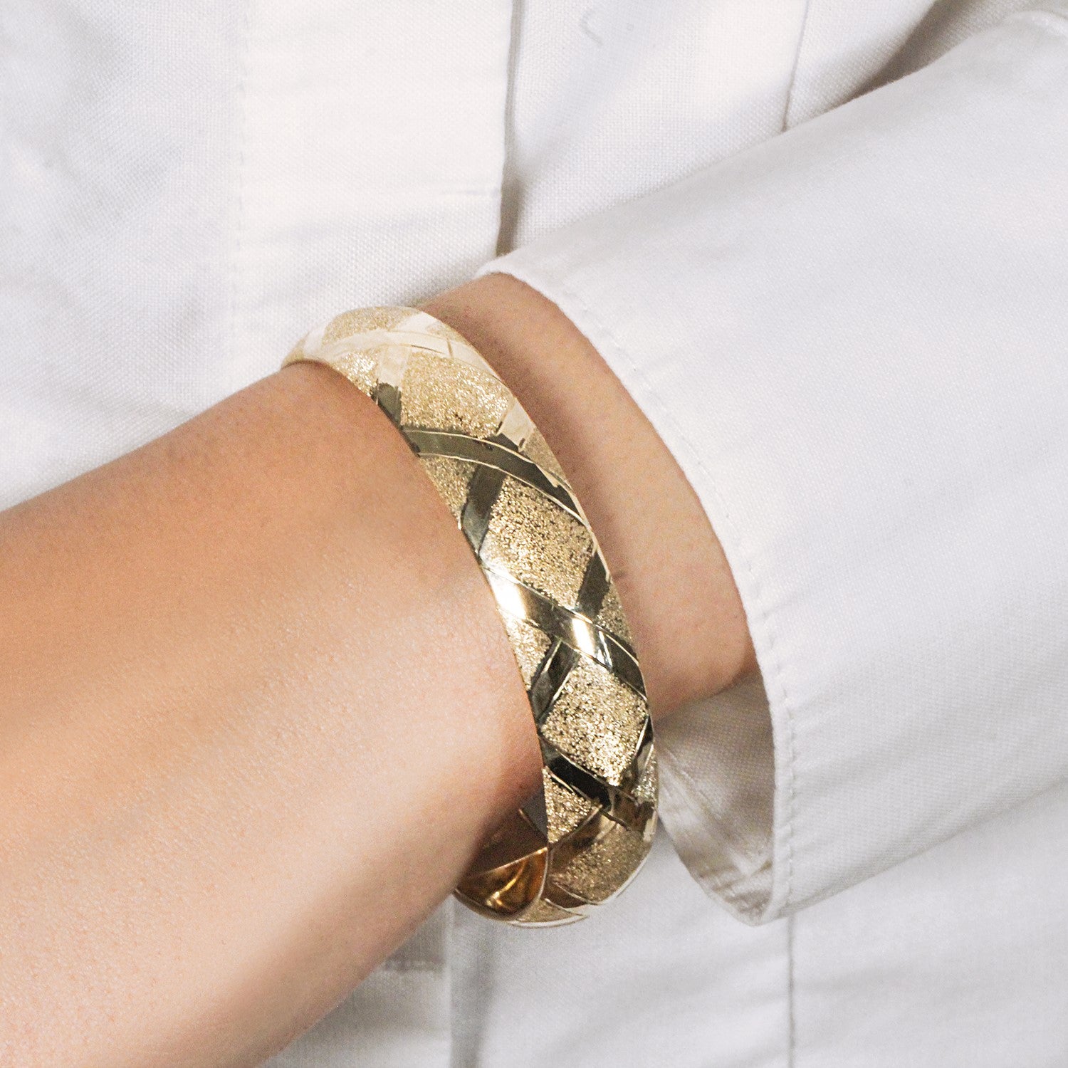 10k yellow gold dual-textured diamond pattern bangle on a person's wrist.