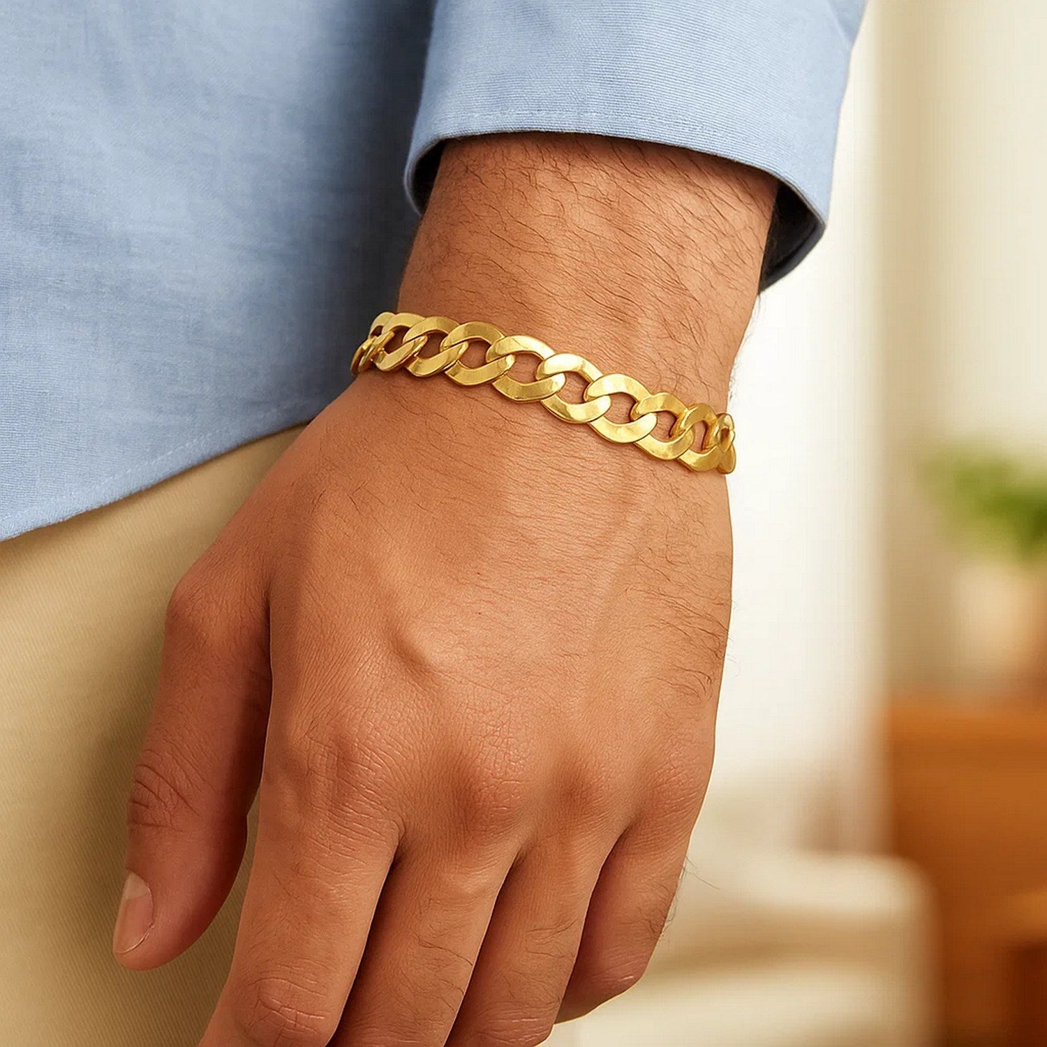 A man's wrist wears a 14k yellow gold solid curb bracelet.