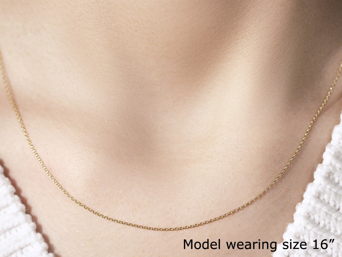18k yellow gold 0.97mm round cable link chain on a model's neck.