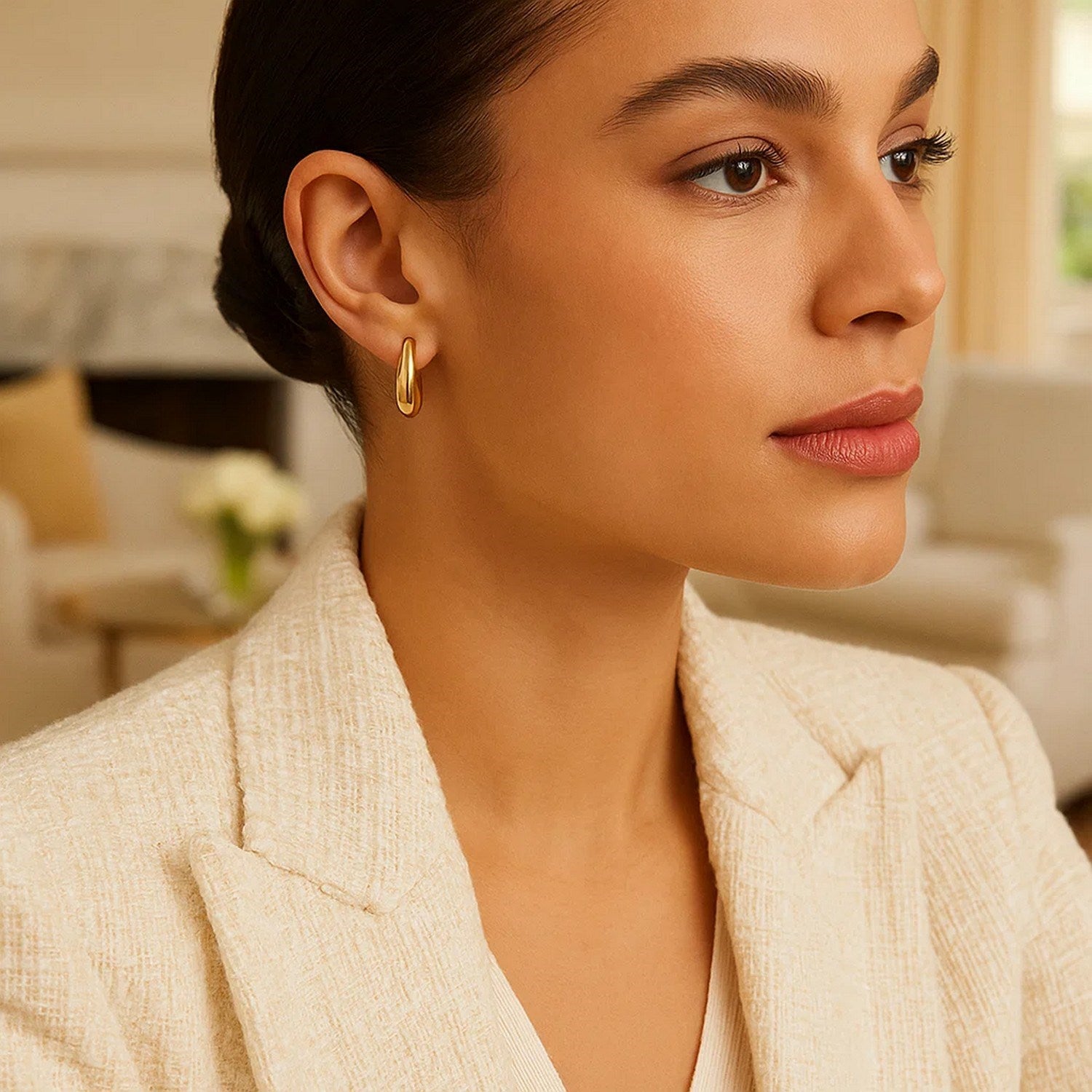 Medium tapered hoop earrings in 14K yellow gold on a model.
