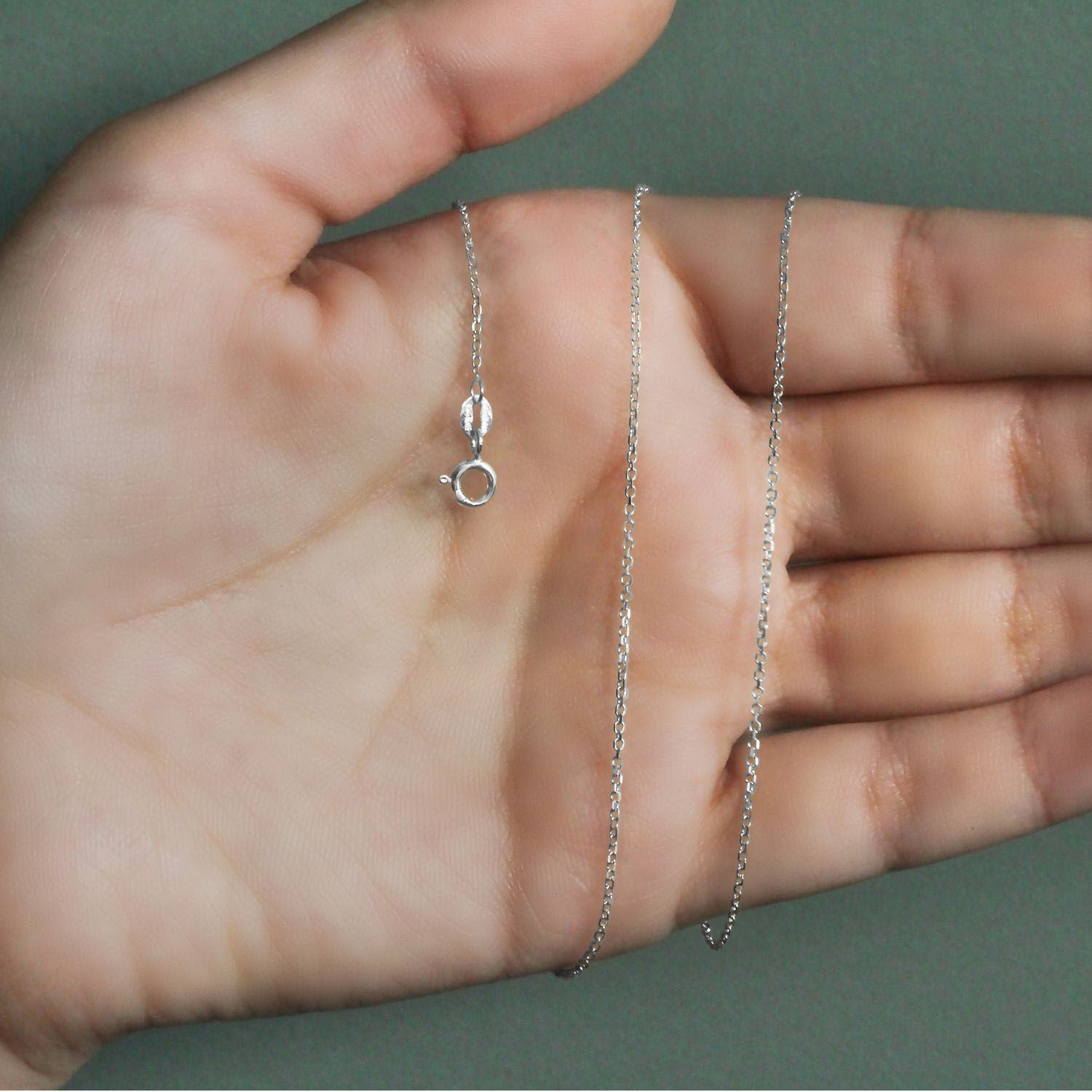 18k white gold diamond cut cable link chain with a spring ring clasp held in a hand.