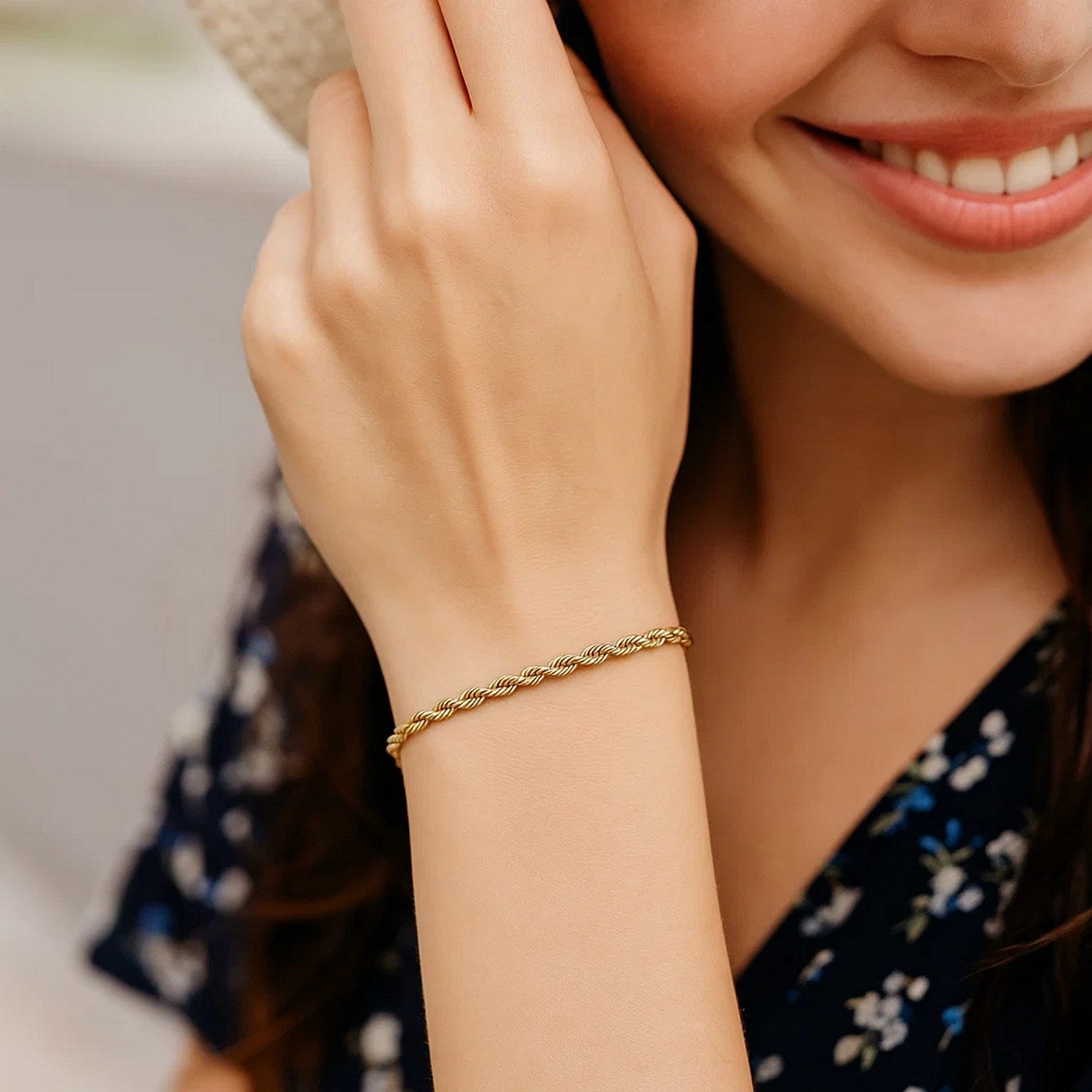 A woman wears a 10k yellow gold solid diamond cut rope bracelet on her wrist.