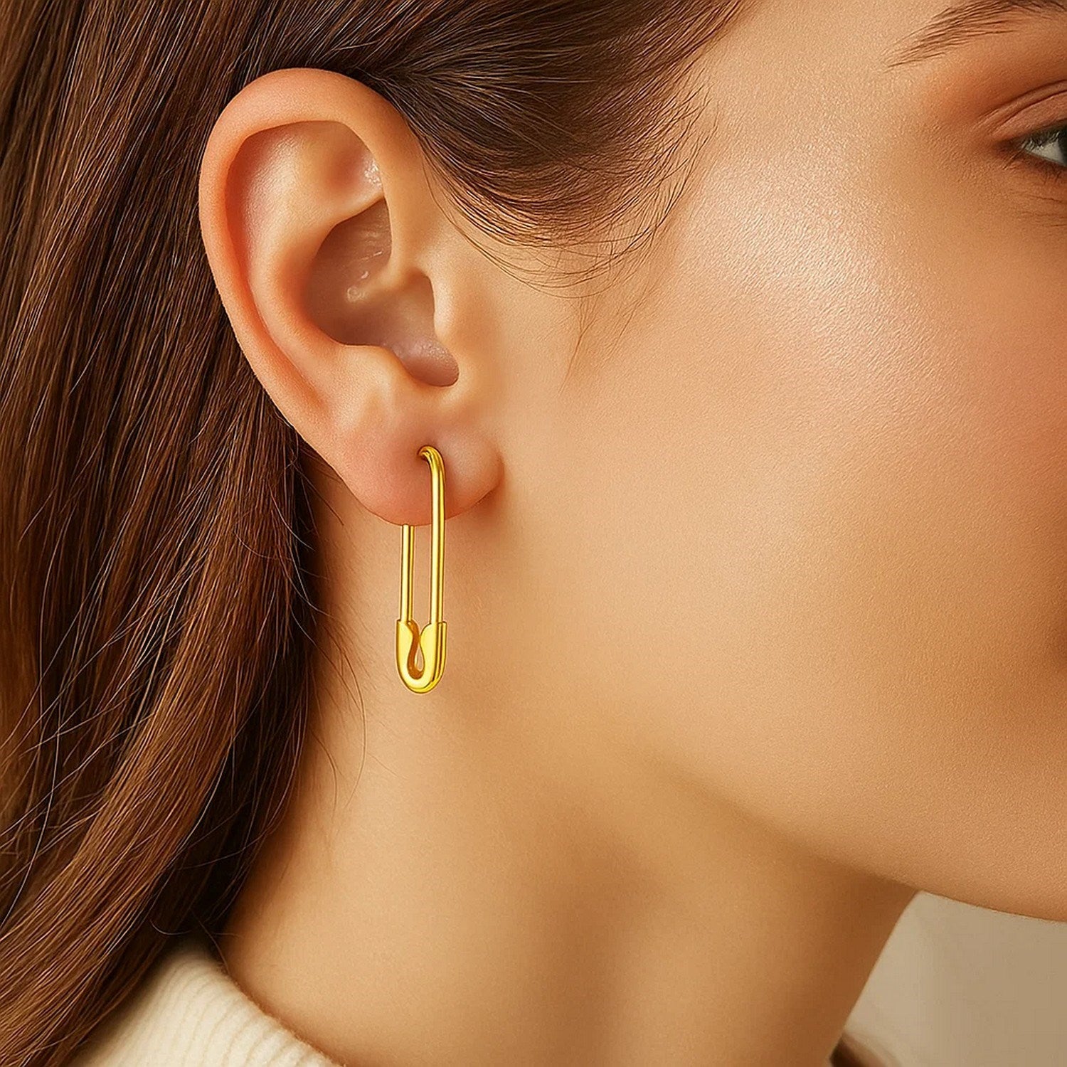 A woman wears 14k yellow gold safety pin earrings.