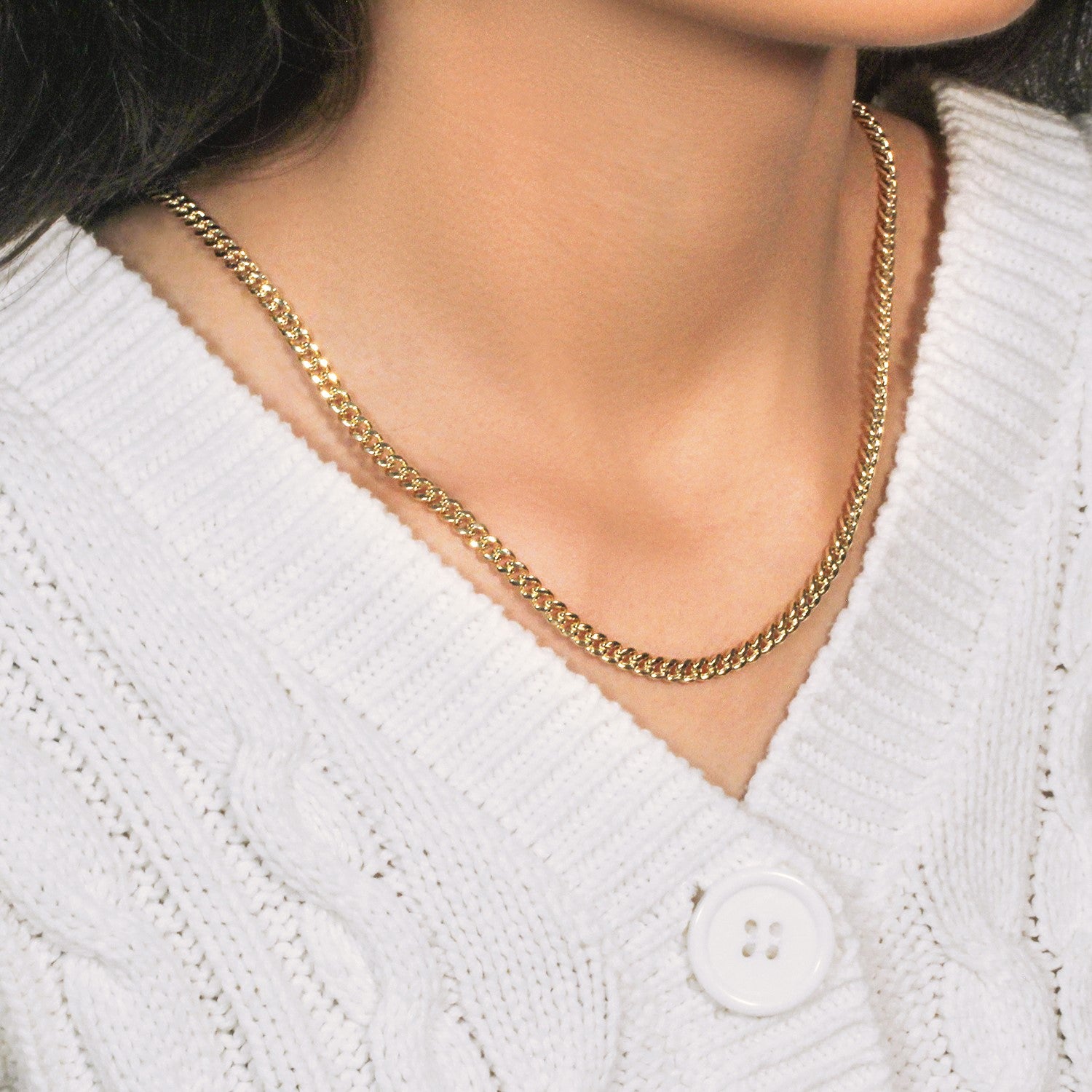 A 14k yellow gold semi-solid Miami Cuban chain is worn over a white cable-knit sweater.