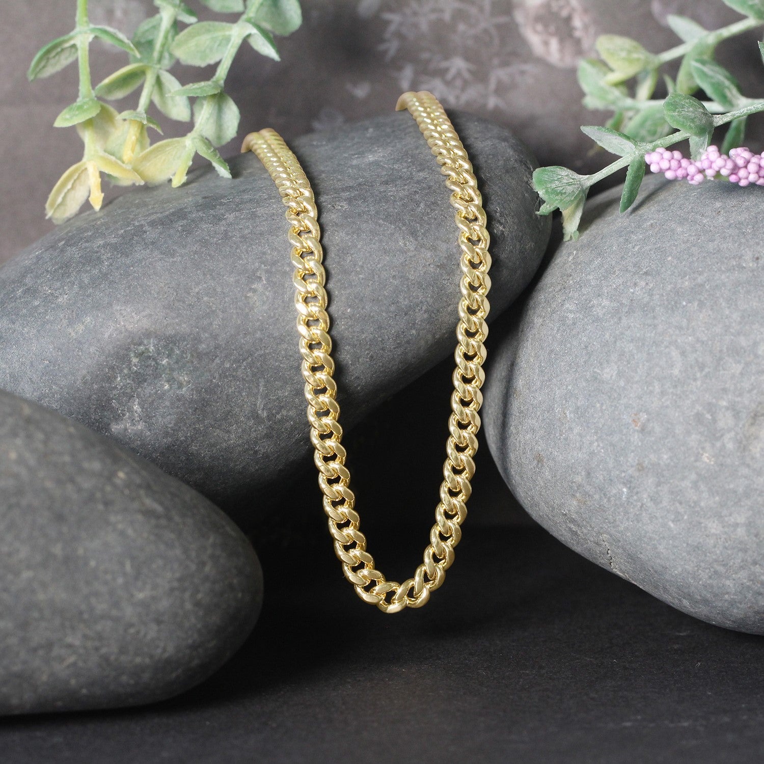 14k yellow gold semi-solid Miami Cuban chain, 4.50 mm wide, draped over dark stones.