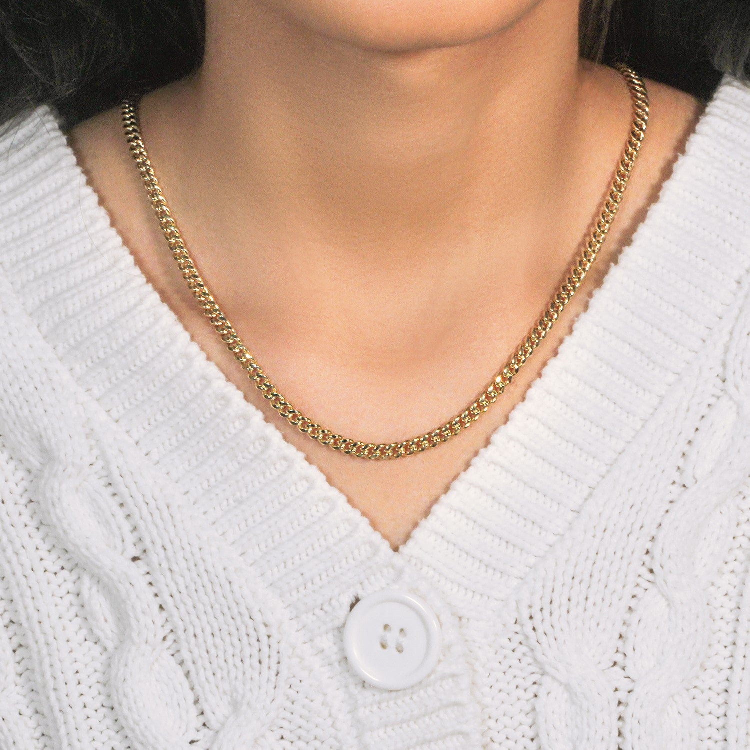 14k yellow gold semi-solid Miami Cuban chain on a person wearing a white sweater.