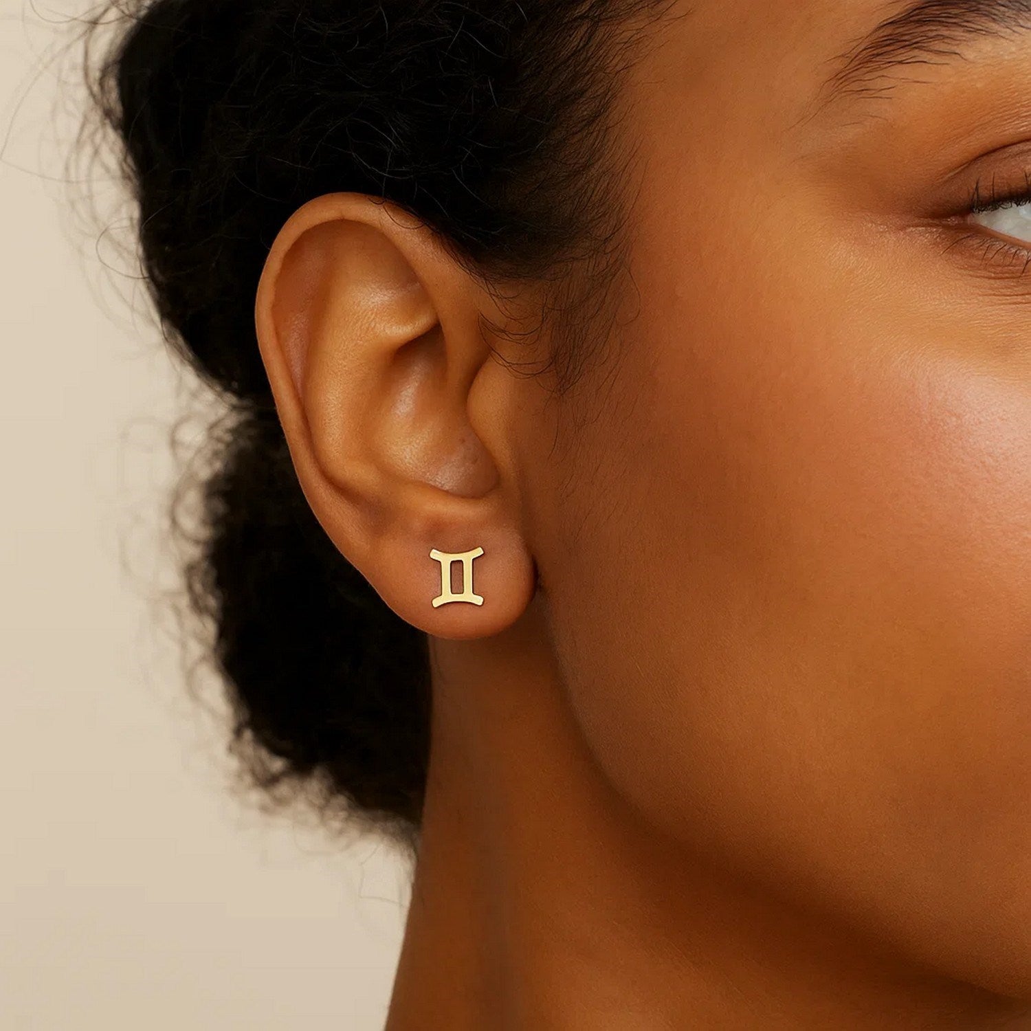 14K yellow gold Gemini stud earring on a person's ear.